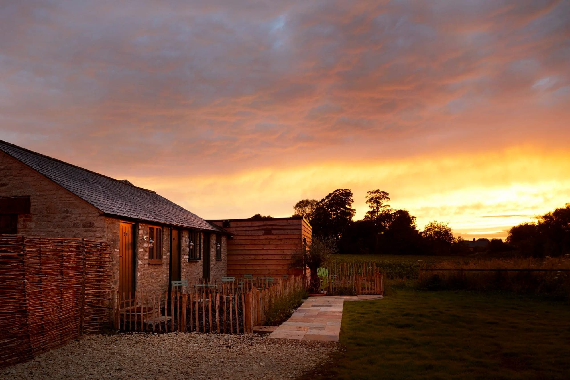 Exterior of stone and wood buildings at sunset with a colorful sky.