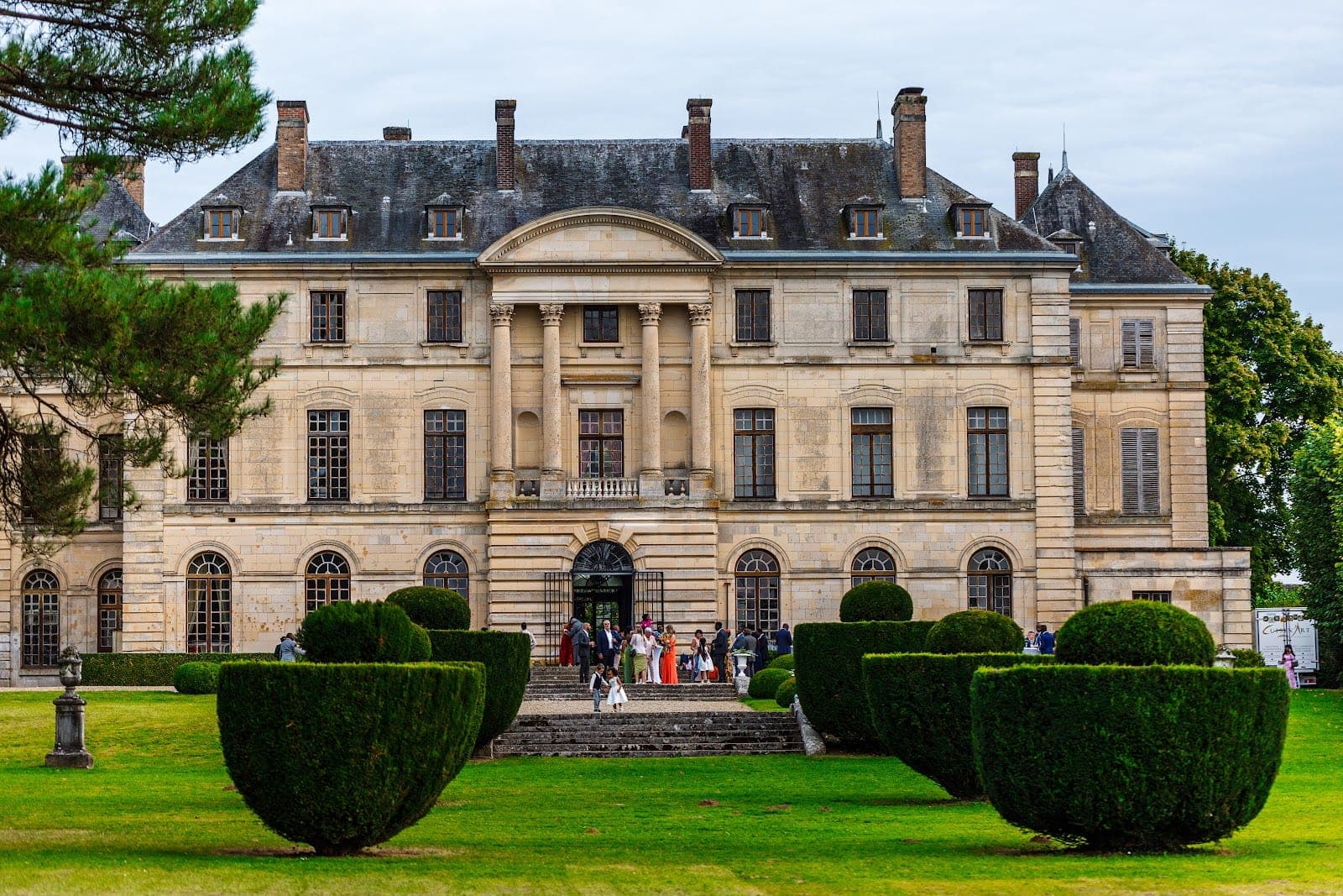 A chateau with a grand entrance and manicured gardens.