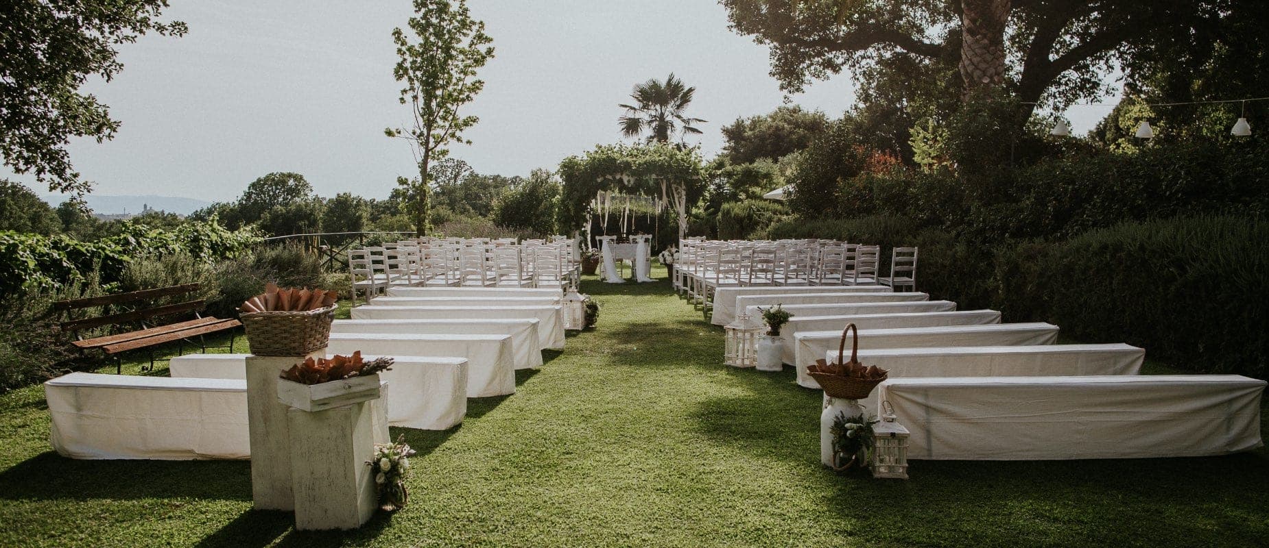 Outdoor wedding ceremony setup with rows of chairs and benches on a lawn.