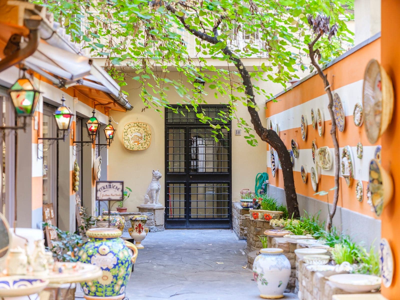 A courtyard with decorative pottery, lanterns, and a statue.