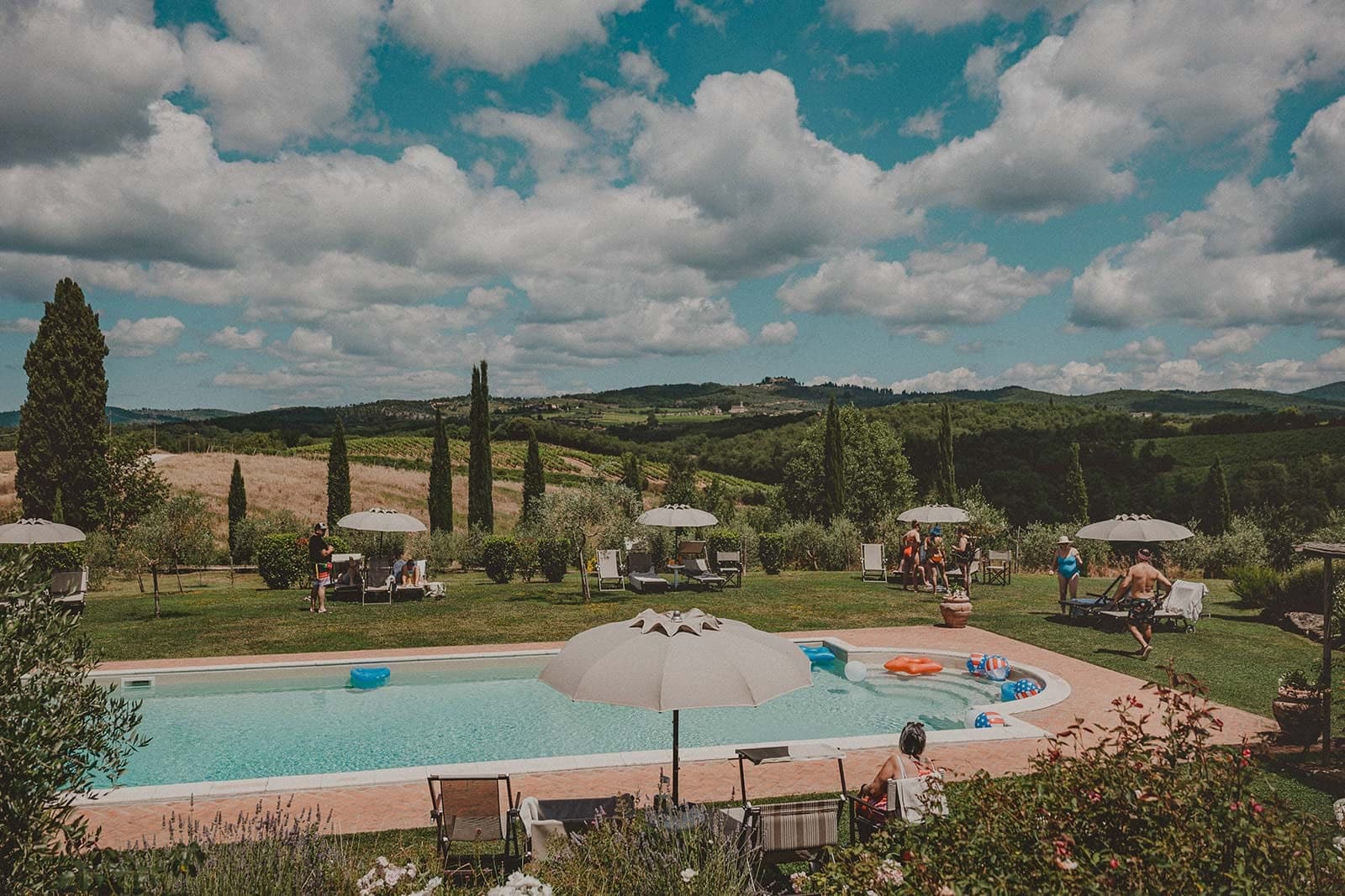 A swimming pool and lawn area with lounge chairs and umbrellas, overlooking rolling hills.