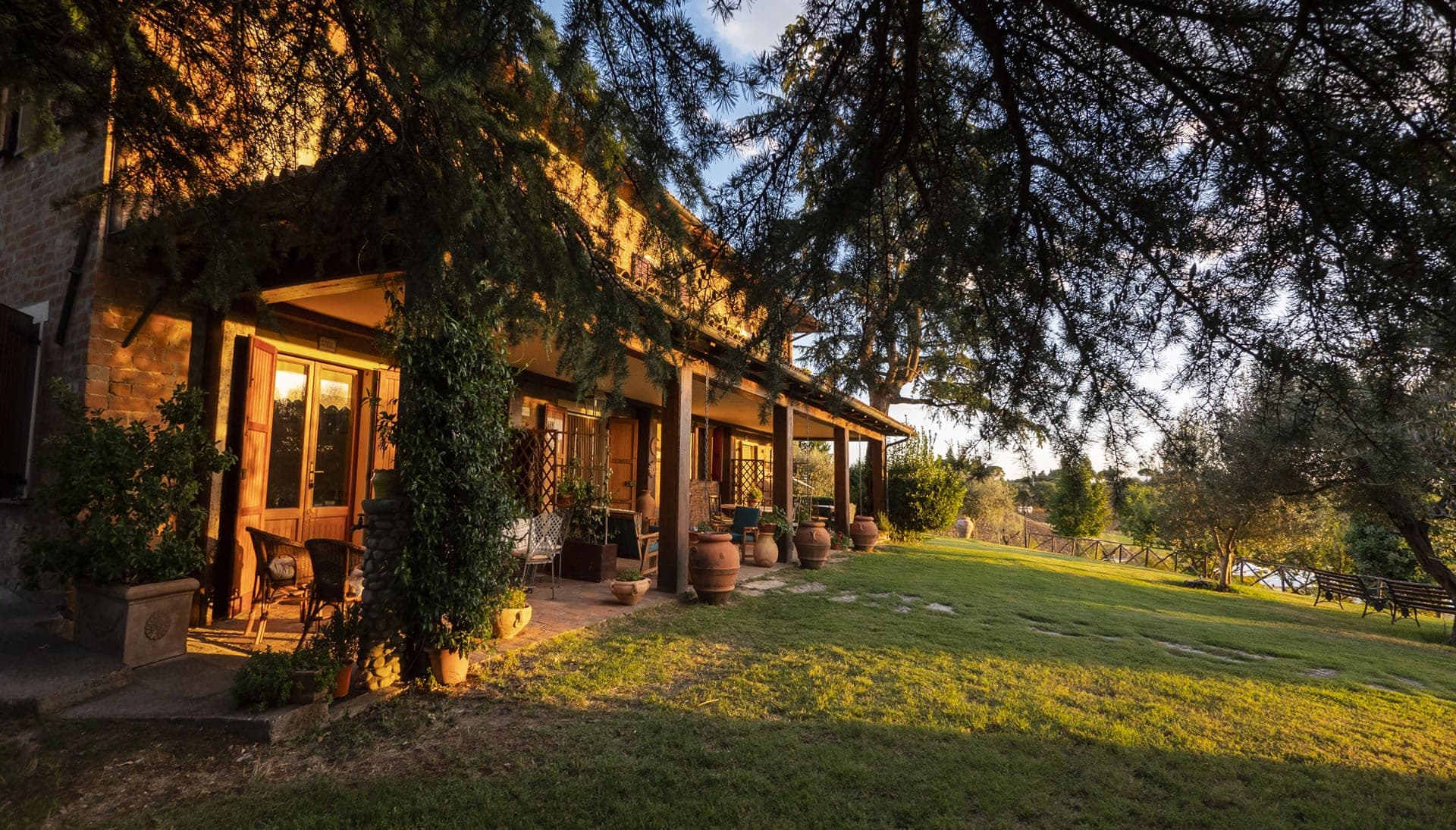 Exterior of a building with a covered porch and lawn at sunset.