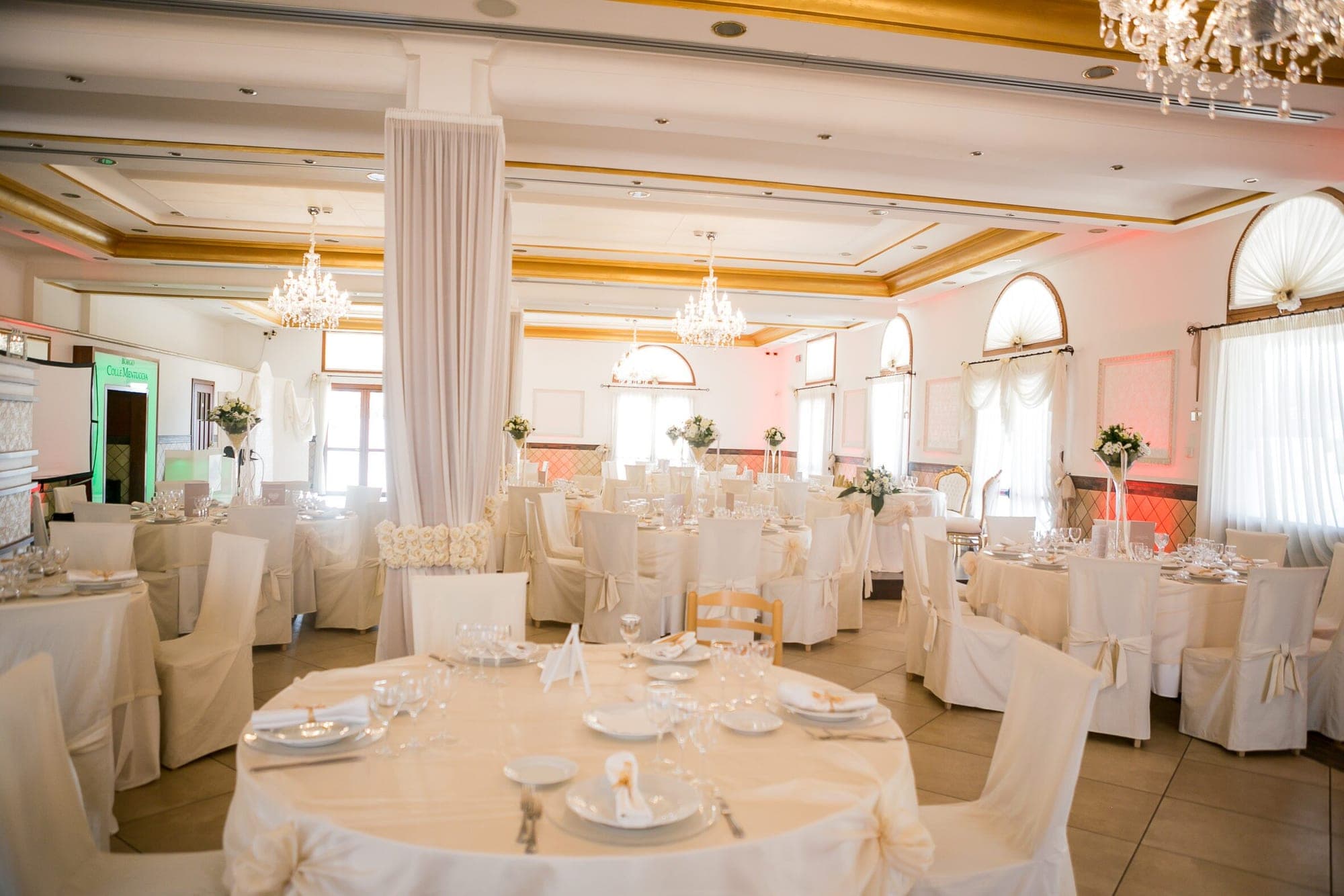A wedding reception room with tables set for guests.