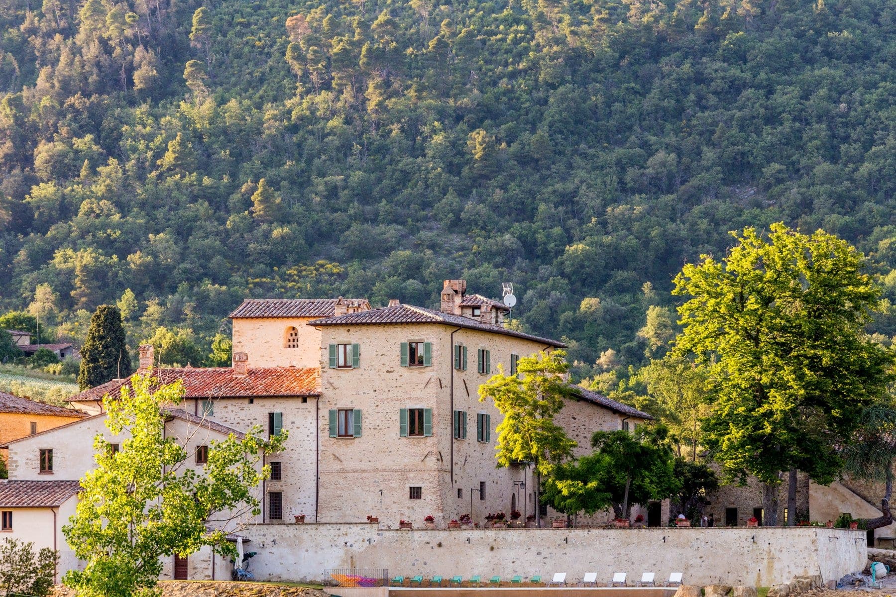 Exterior of Borgo Colognola with a swimming pool and surrounding trees.