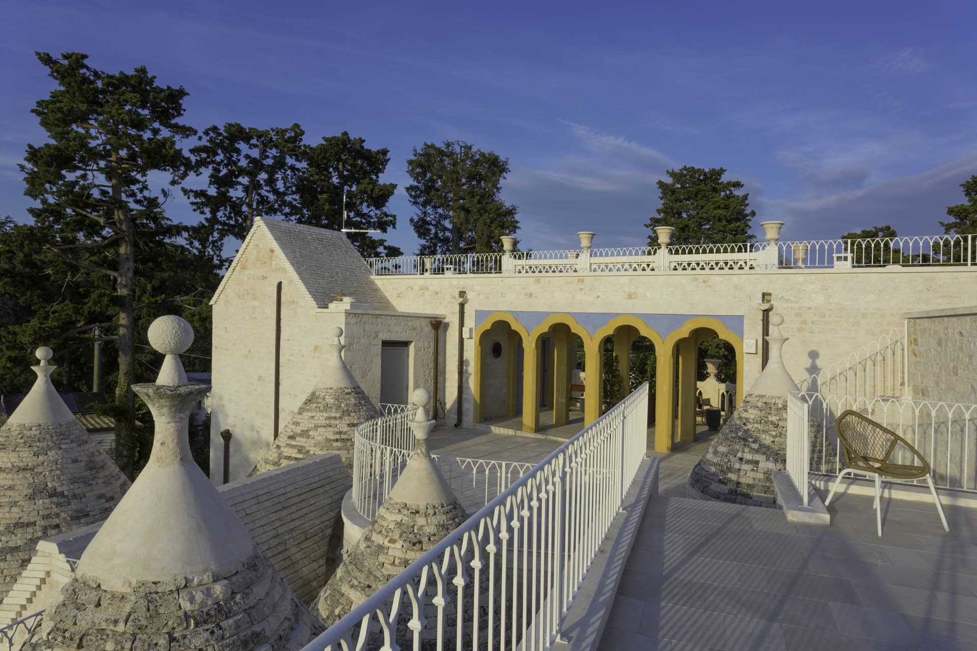 Exterior view of a white building with conical roofs and arched yellow doorways.