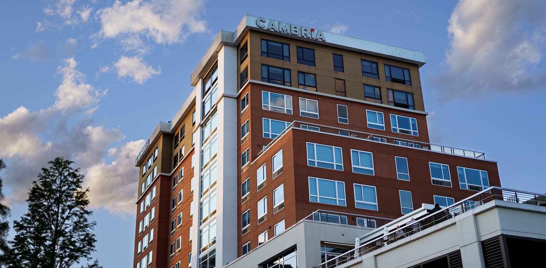 Exterior of the Cambria Hotel building with a blue sky and clouds.