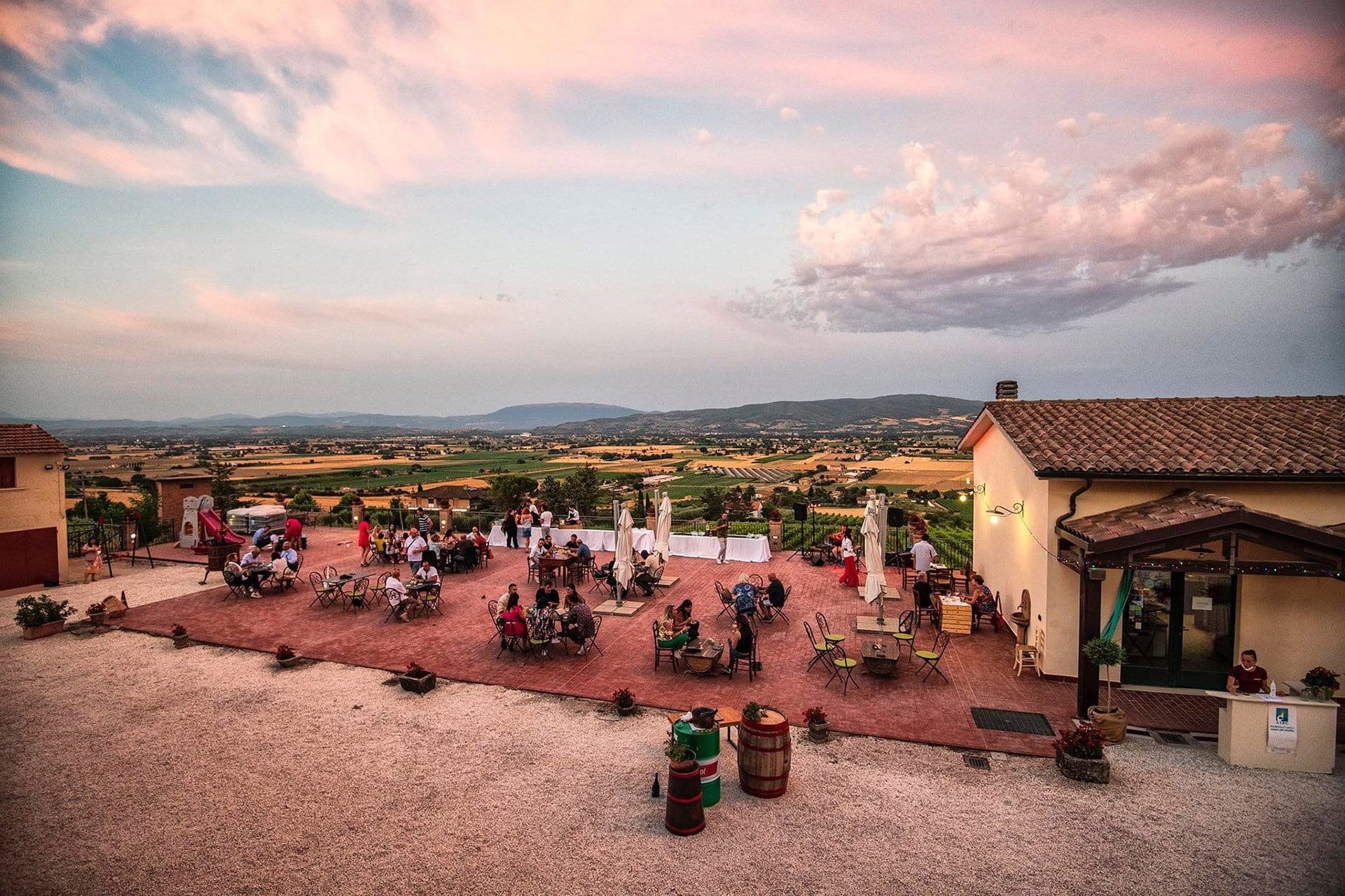 Terrace with tables and people at sunset overlooking a valley