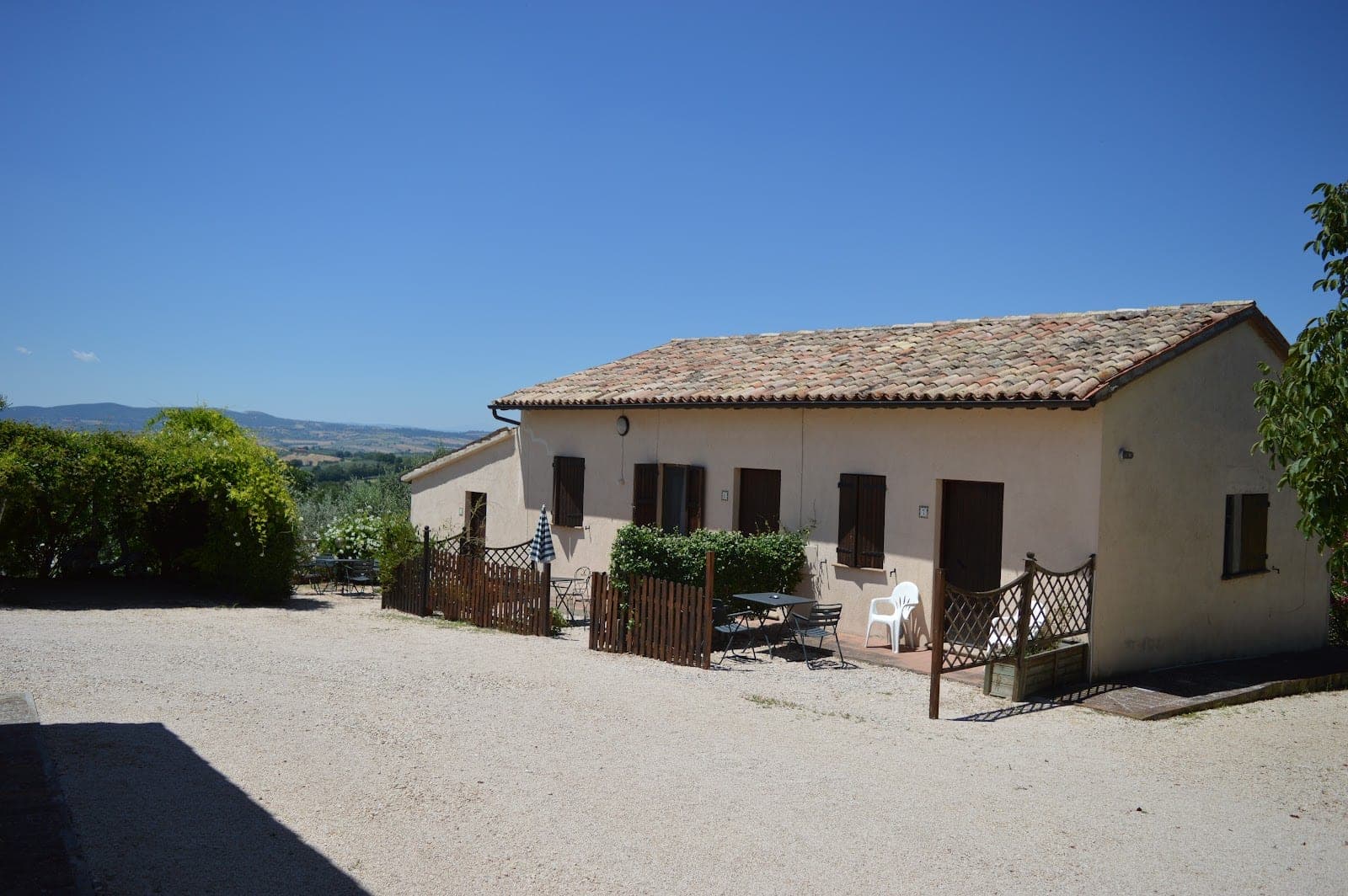 Exterior of a building with a tiled roof and shutters, set against a clear blue sky.