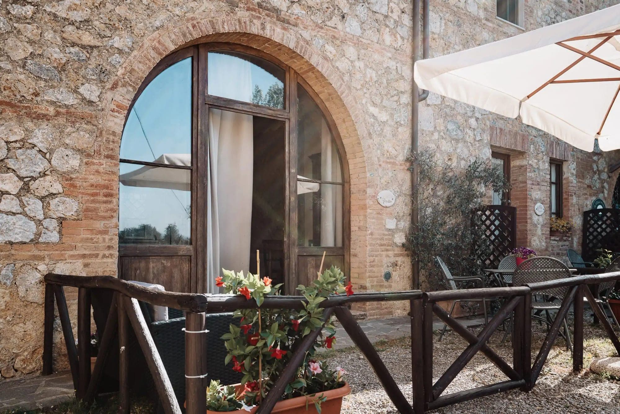 Arched doorway and patio with tables and chairs at a rustic venue.