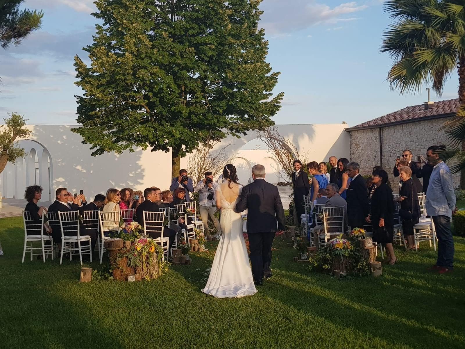Outdoor wedding ceremony with guests seated and wedding party walking down aisle.