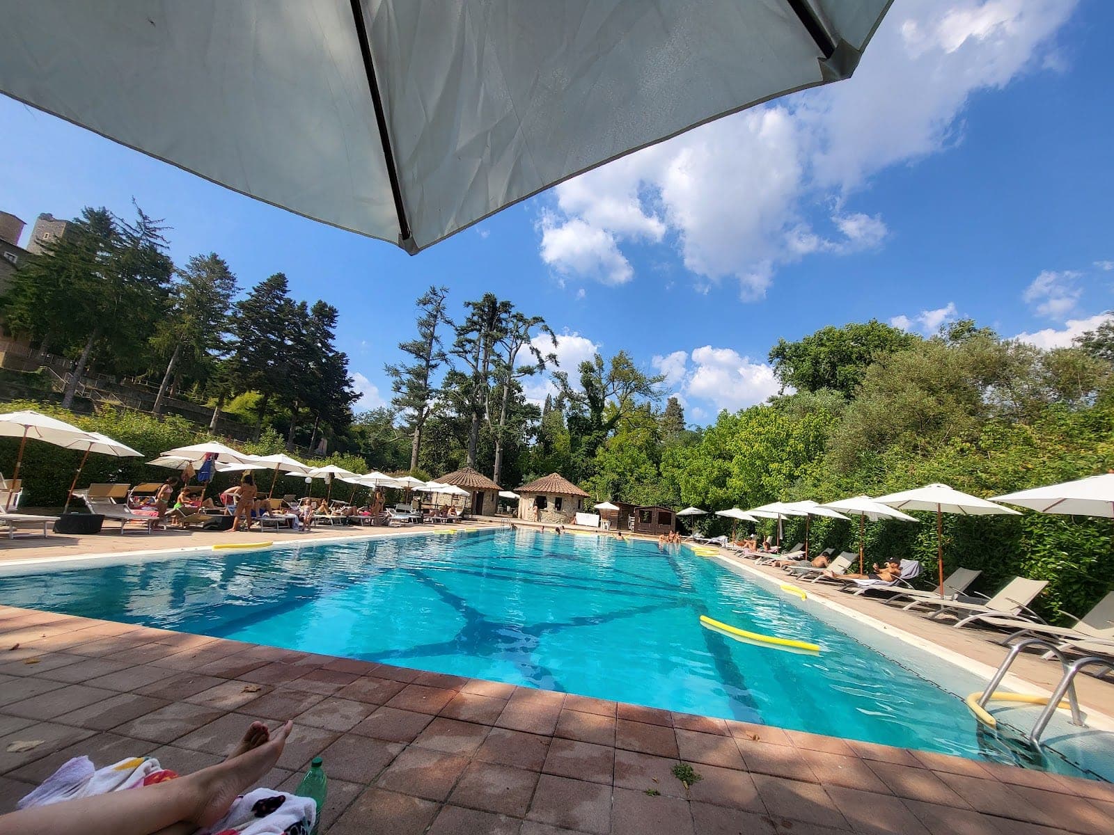 A swimming pool with lounge chairs and umbrellas under a blue sky.