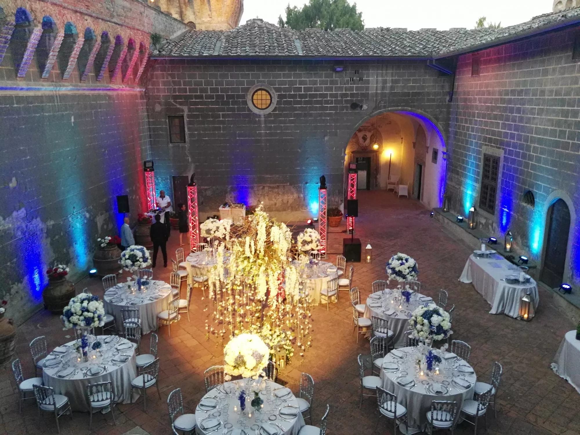 Courtyard reception setup with tables, chairs, and floral decorations.
