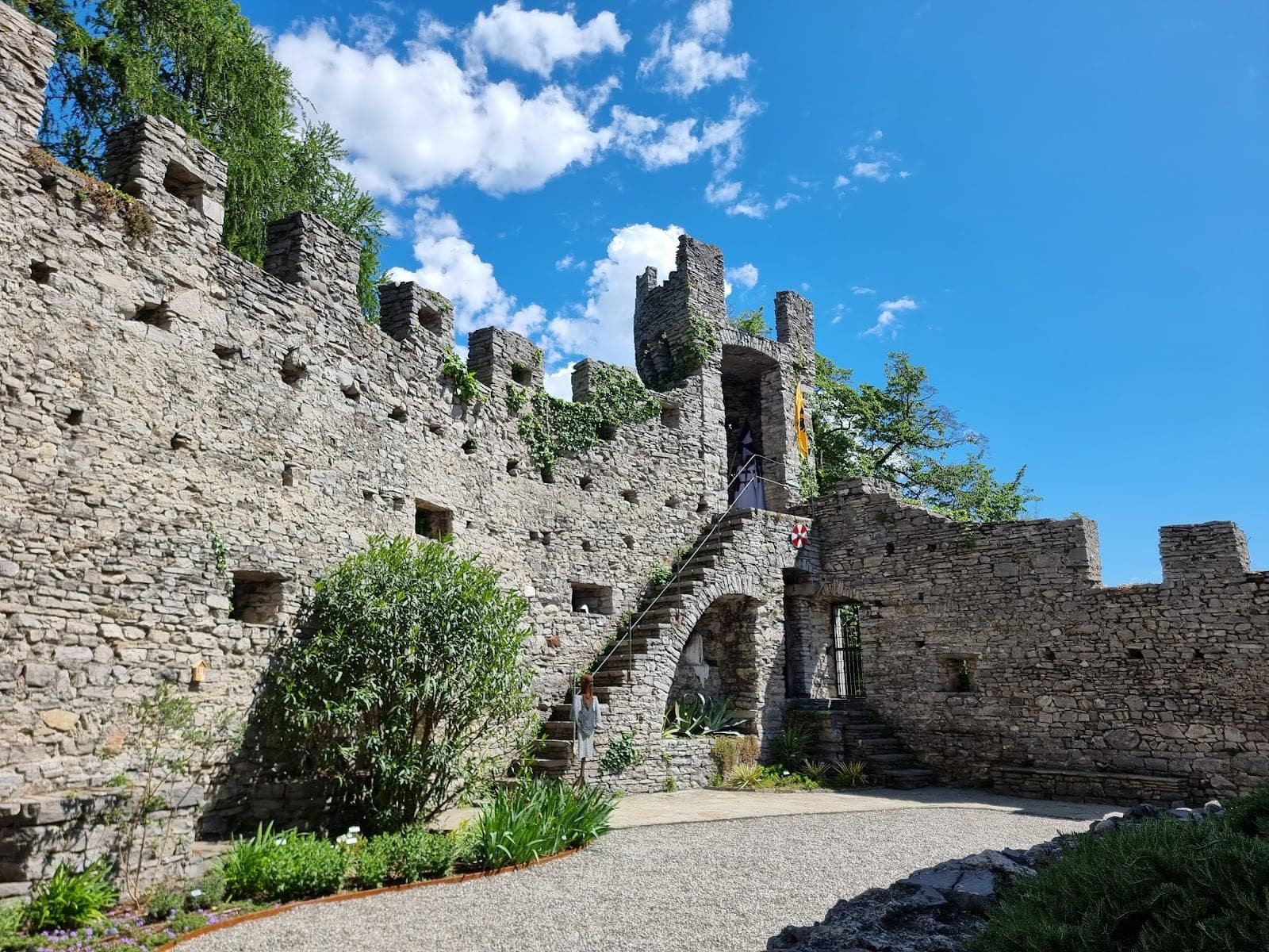 Stone castle wall with a staircase and a person walking up it.