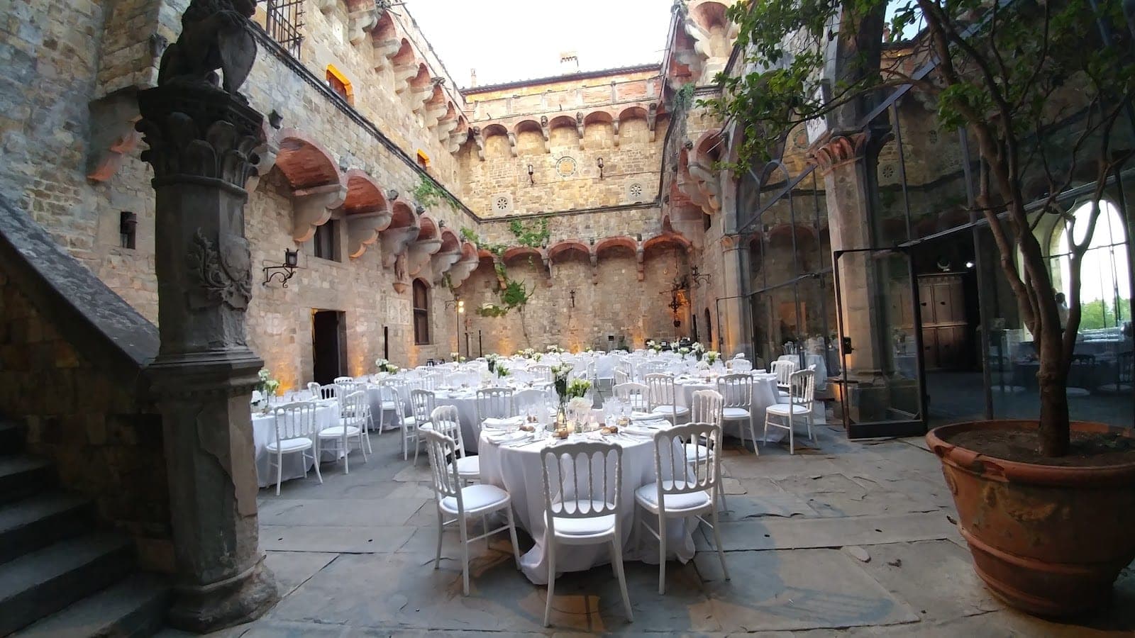 A courtyard with tables and chairs set up for a wedding reception.