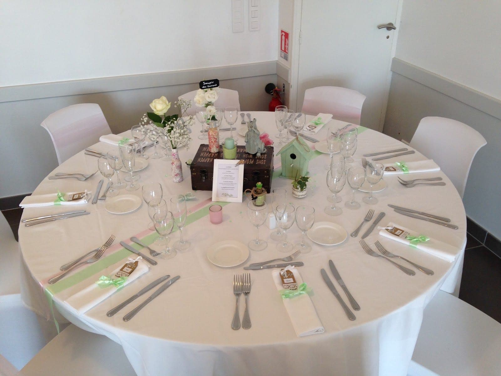 A round wedding reception table set with white linens, place settings, and floral centerpieces.