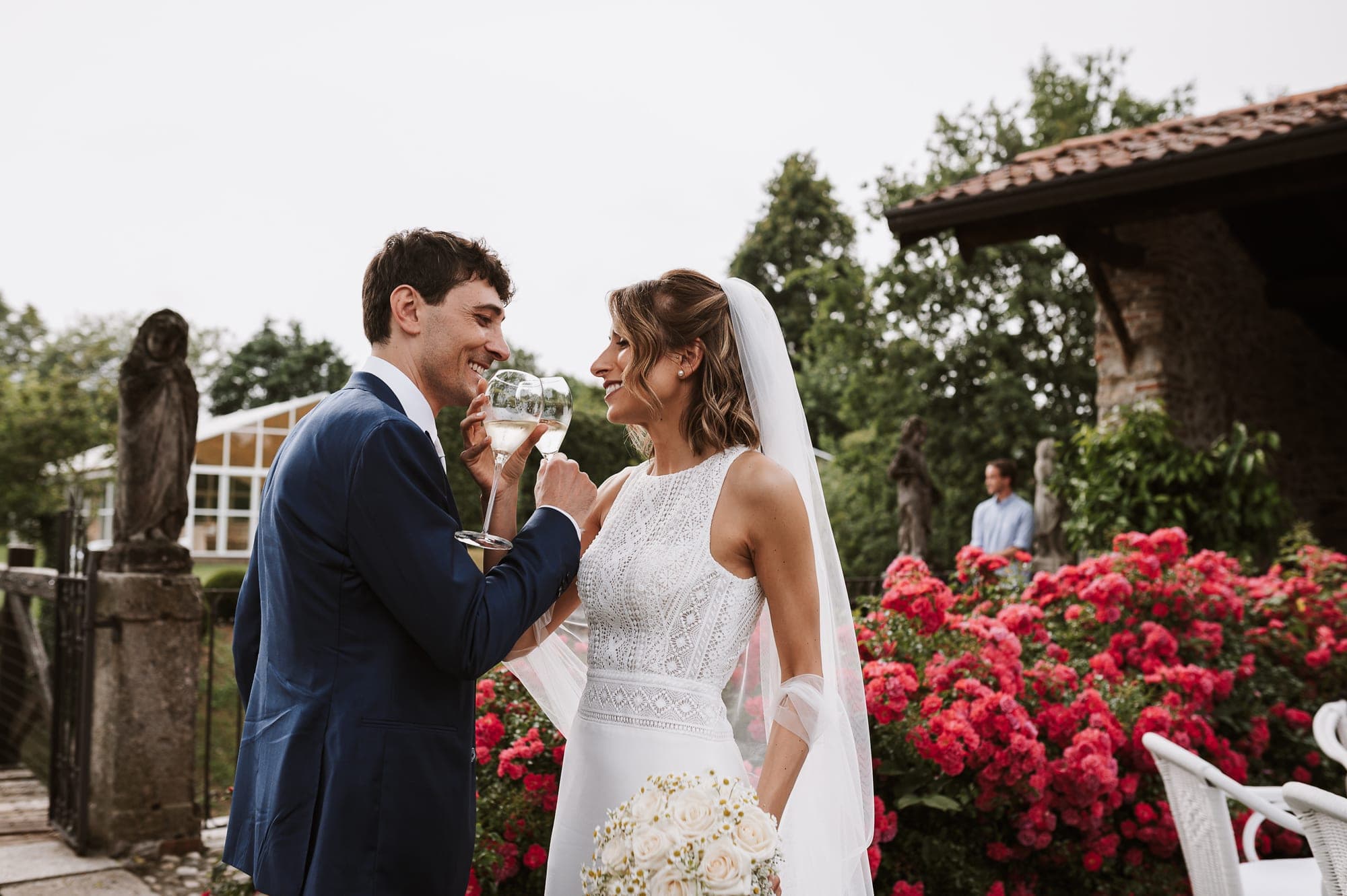 Bride and groom toasting with champagne in a garden.