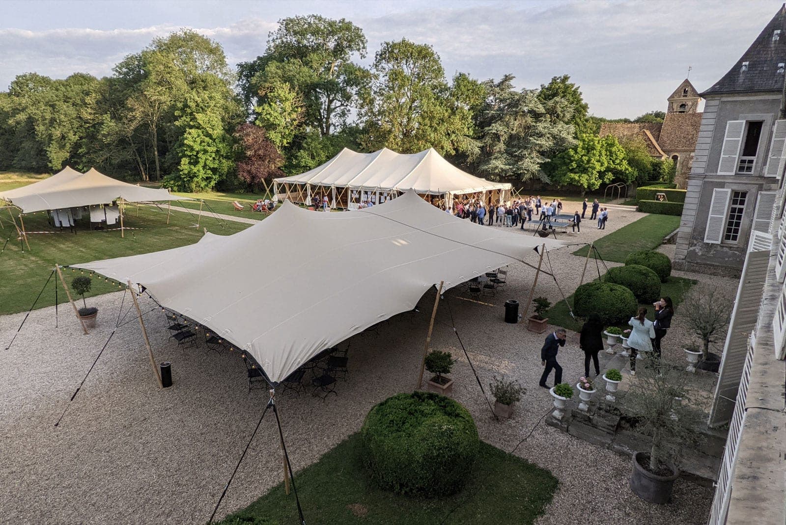 Wedding reception tents set up in a courtyard with a chateau in the background.