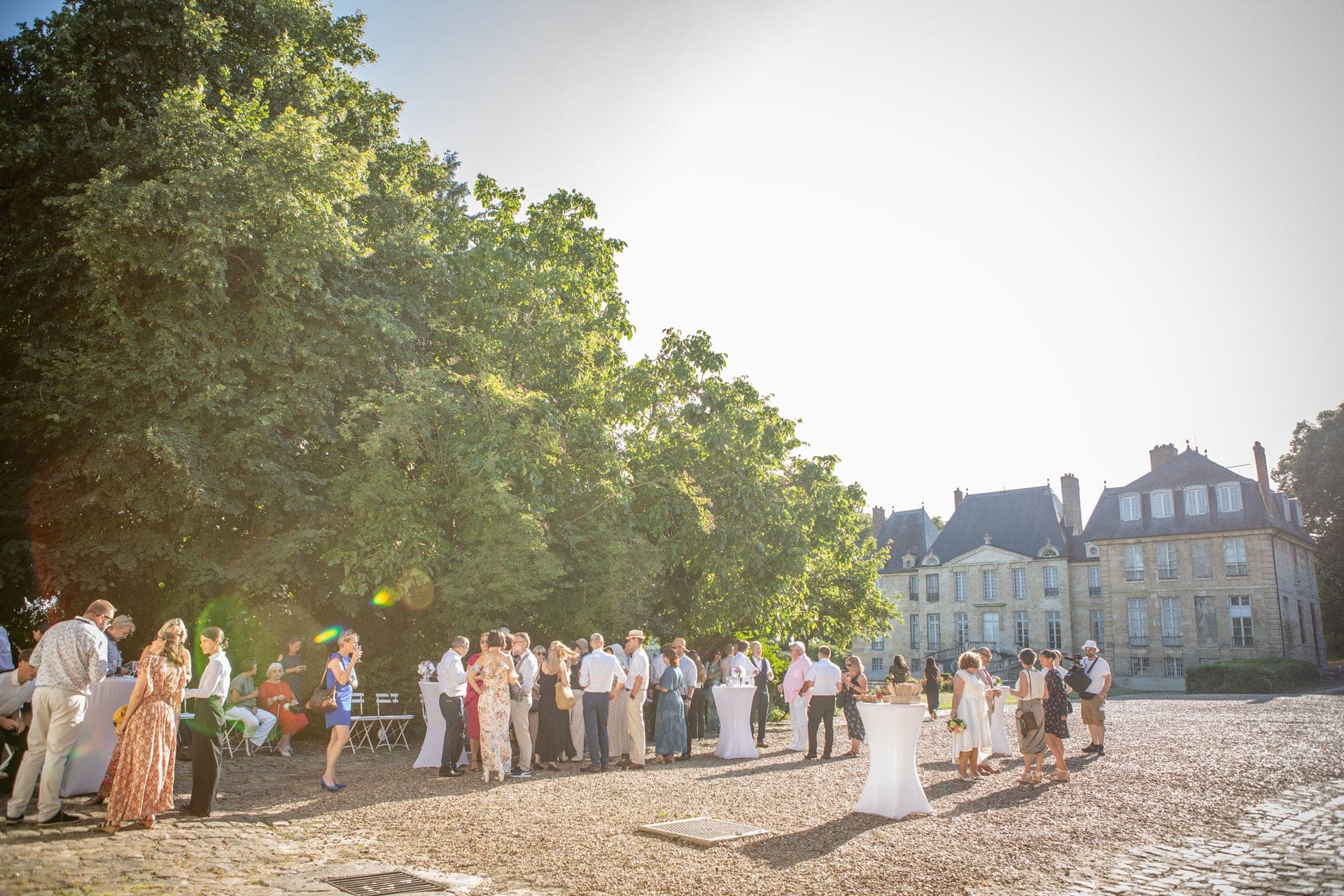 Guests mingling in the courtyard of a chateau during a wedding reception.