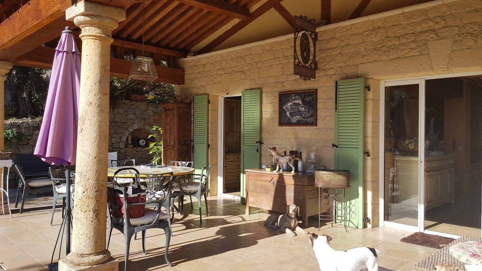 Covered terrace with dining table, chairs, and dogs.