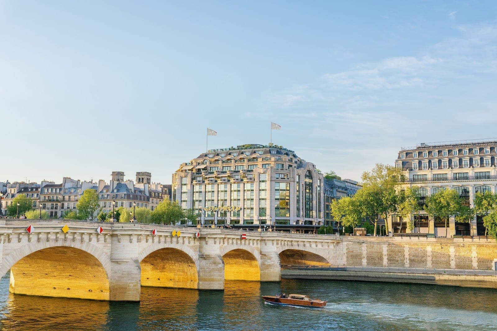 Exterior of Cheval Blanc Paris hotel on the Seine river with a bridge.