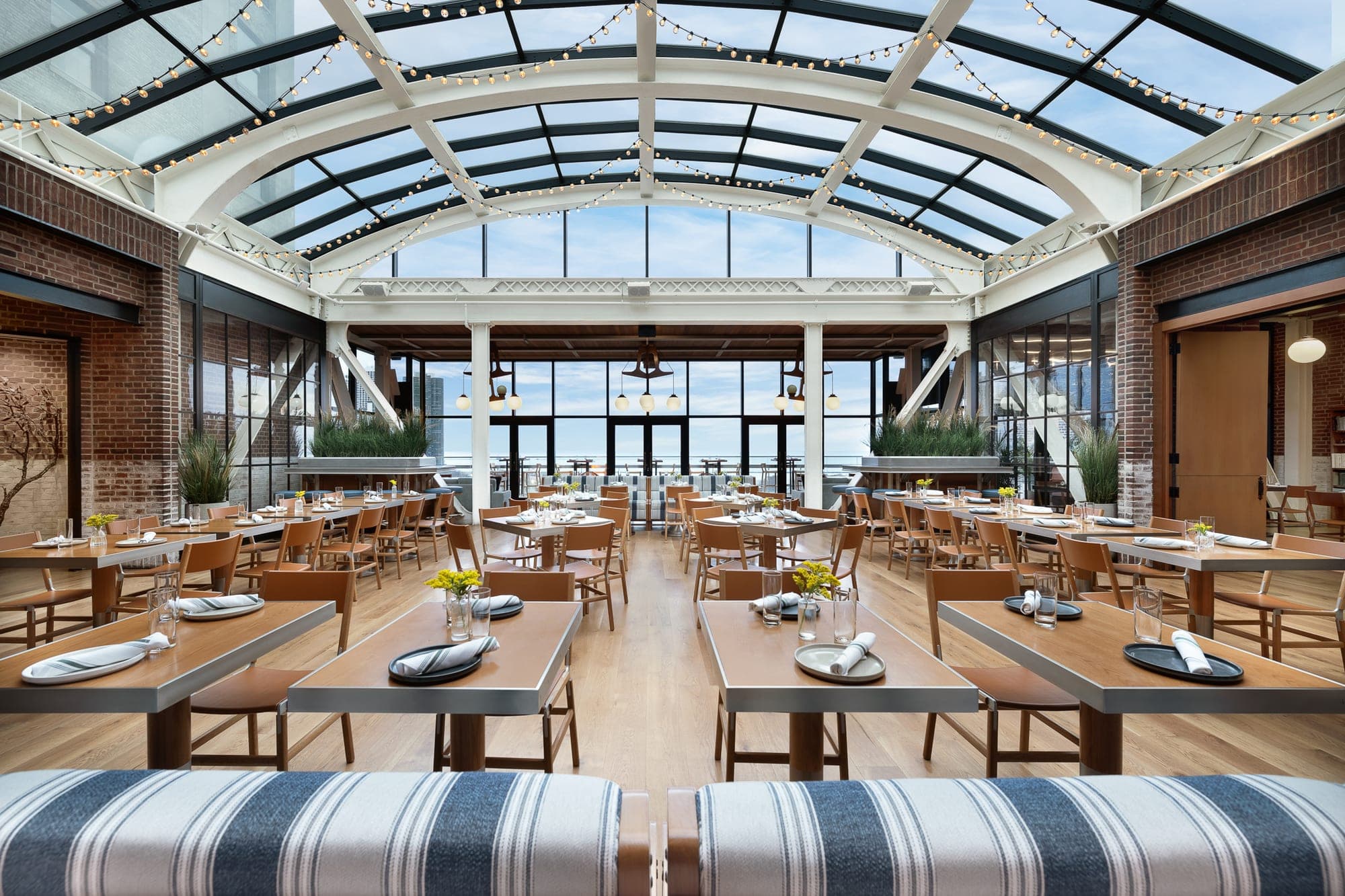 Dining room with tables set for a reception under a glass ceiling.