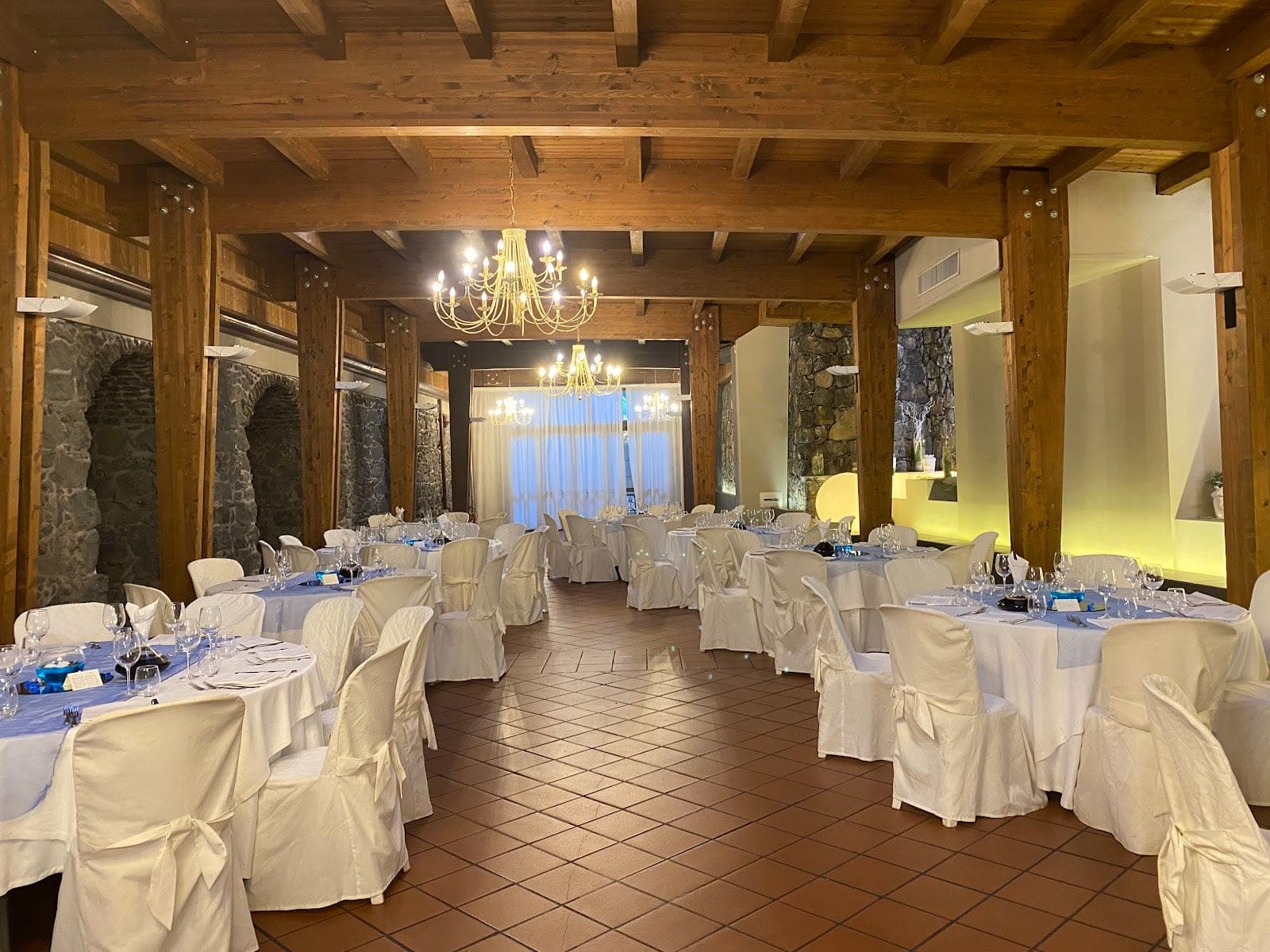 A reception room with tables set for a wedding, featuring white tablecloths and blue runners.