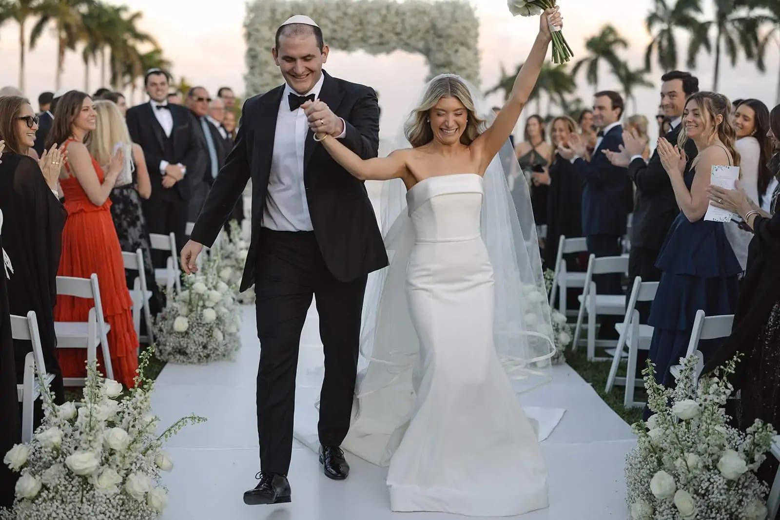 A bride and groom walk down an aisle at their wedding ceremony.
