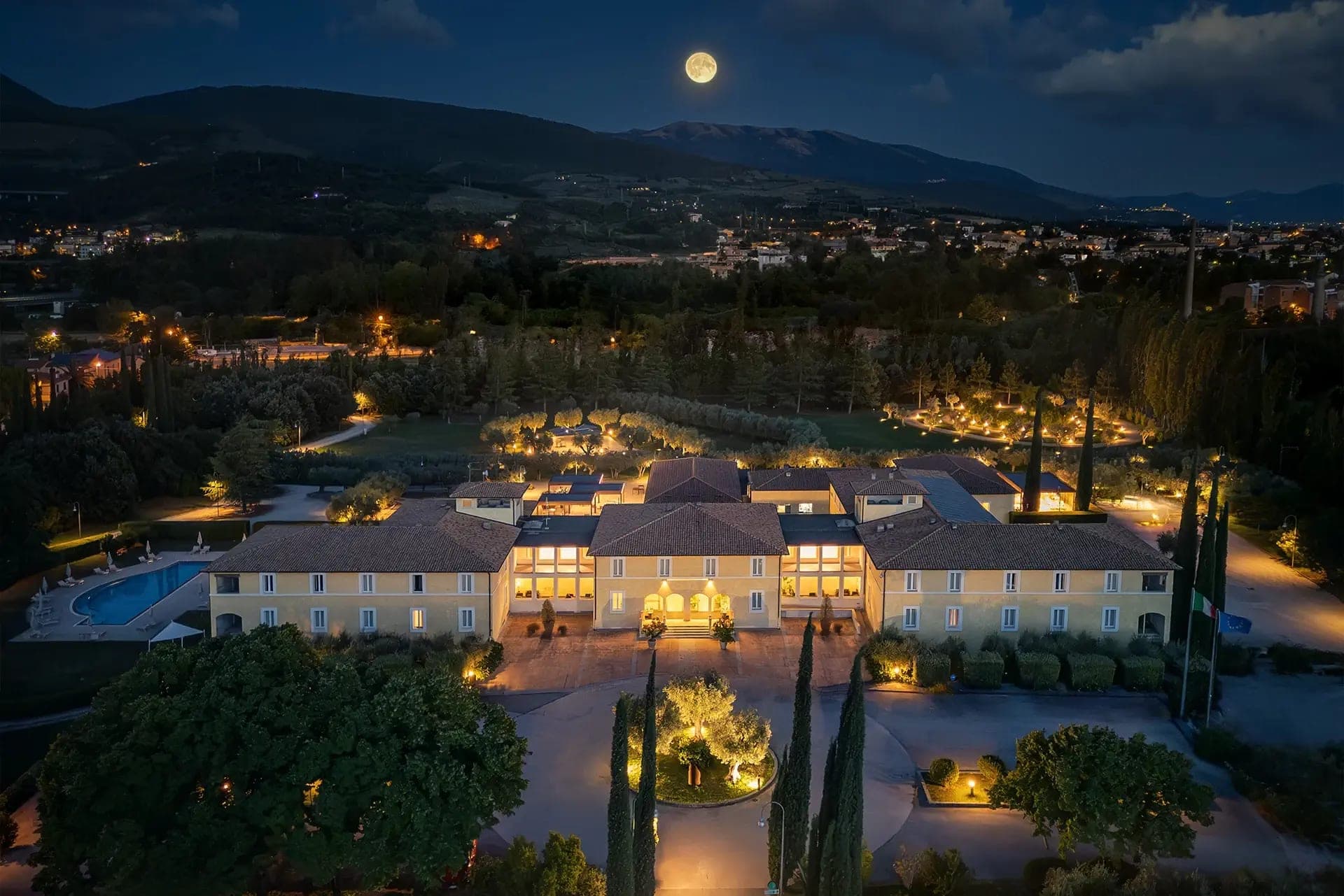 The Delfina Palace Hotel exterior at night with a full moon overhead.