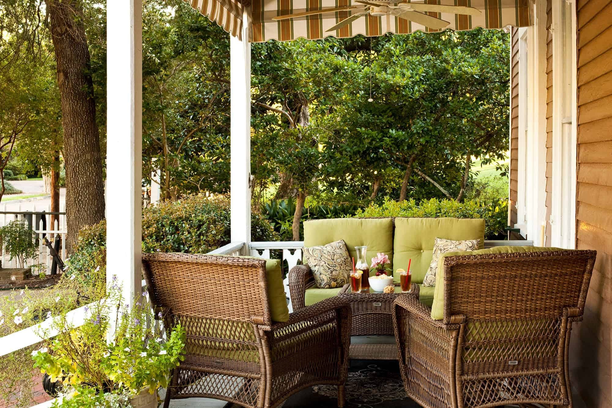 A covered porch with wicker furniture and drinks.