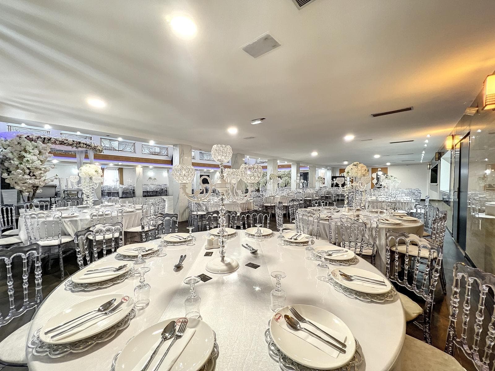 A reception hall with round and oval tables set for a wedding.