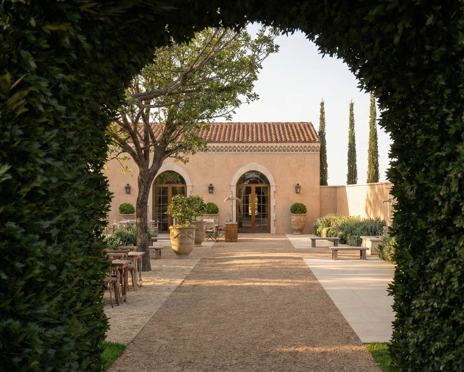 Courtyard with tables and chairs outside a building with a tiled roof.