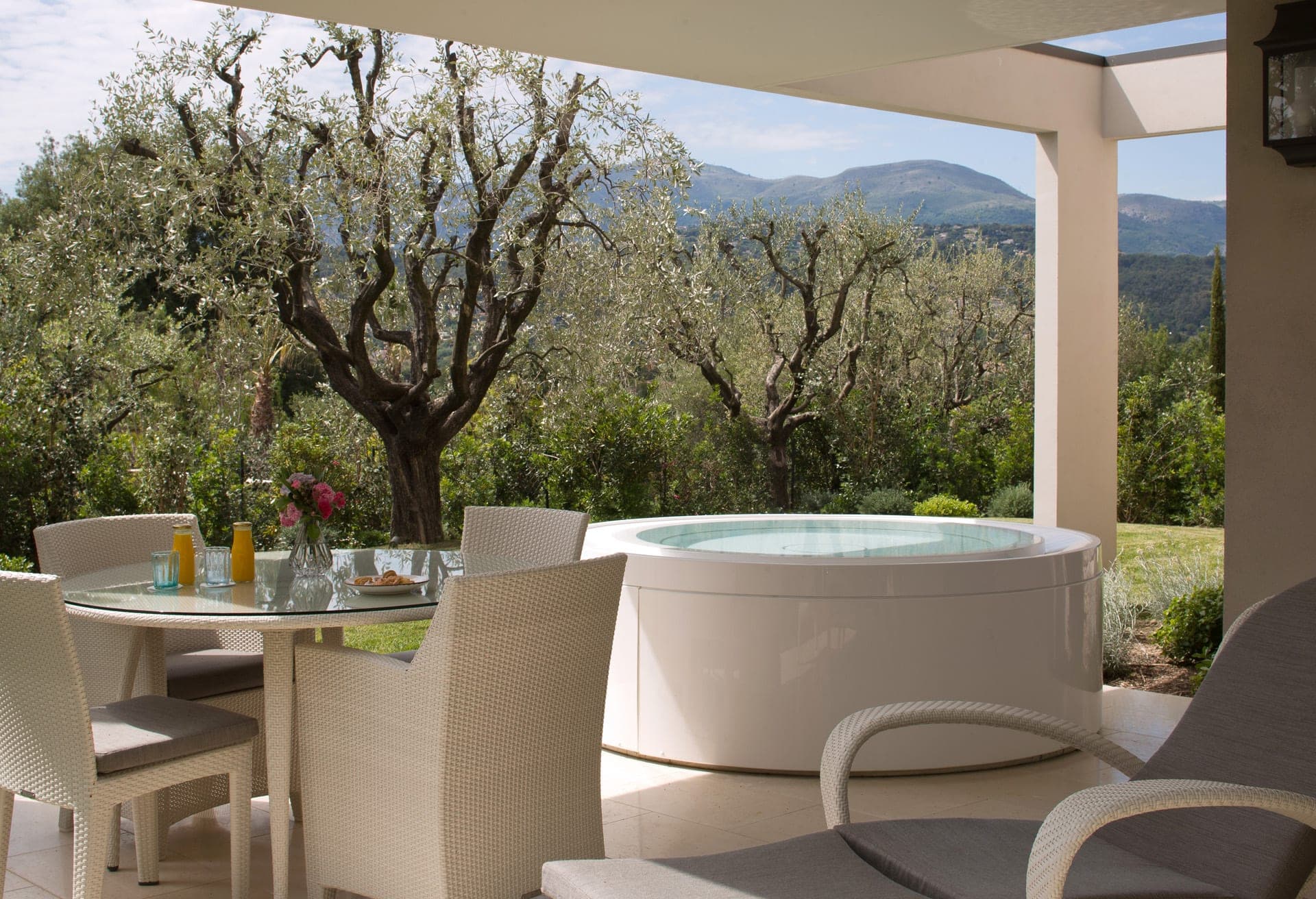 Patio with hot tub and dining table overlooking garden and hills