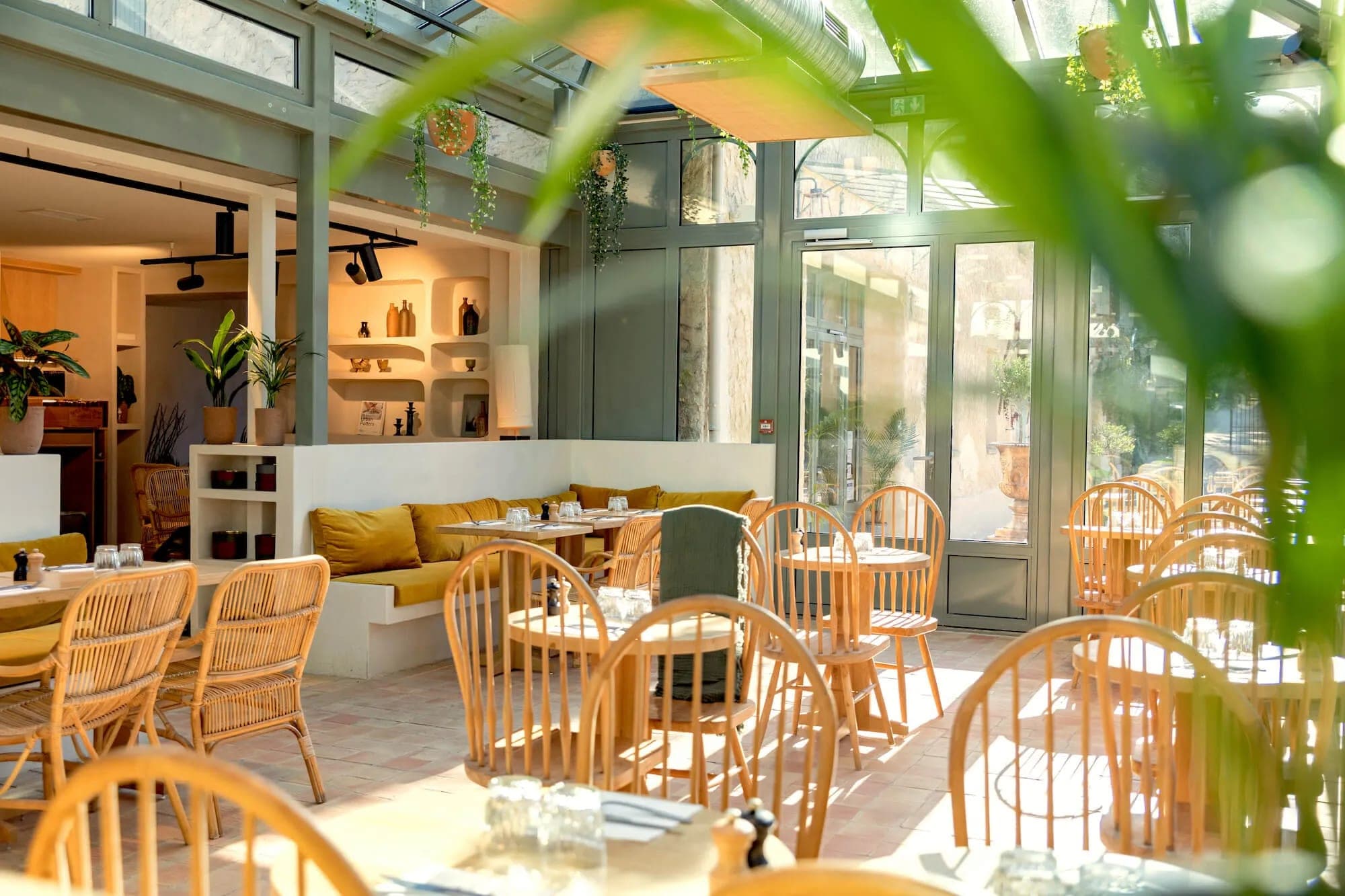 Indoor dining area with wooden tables and chairs, and yellow banquette seating.