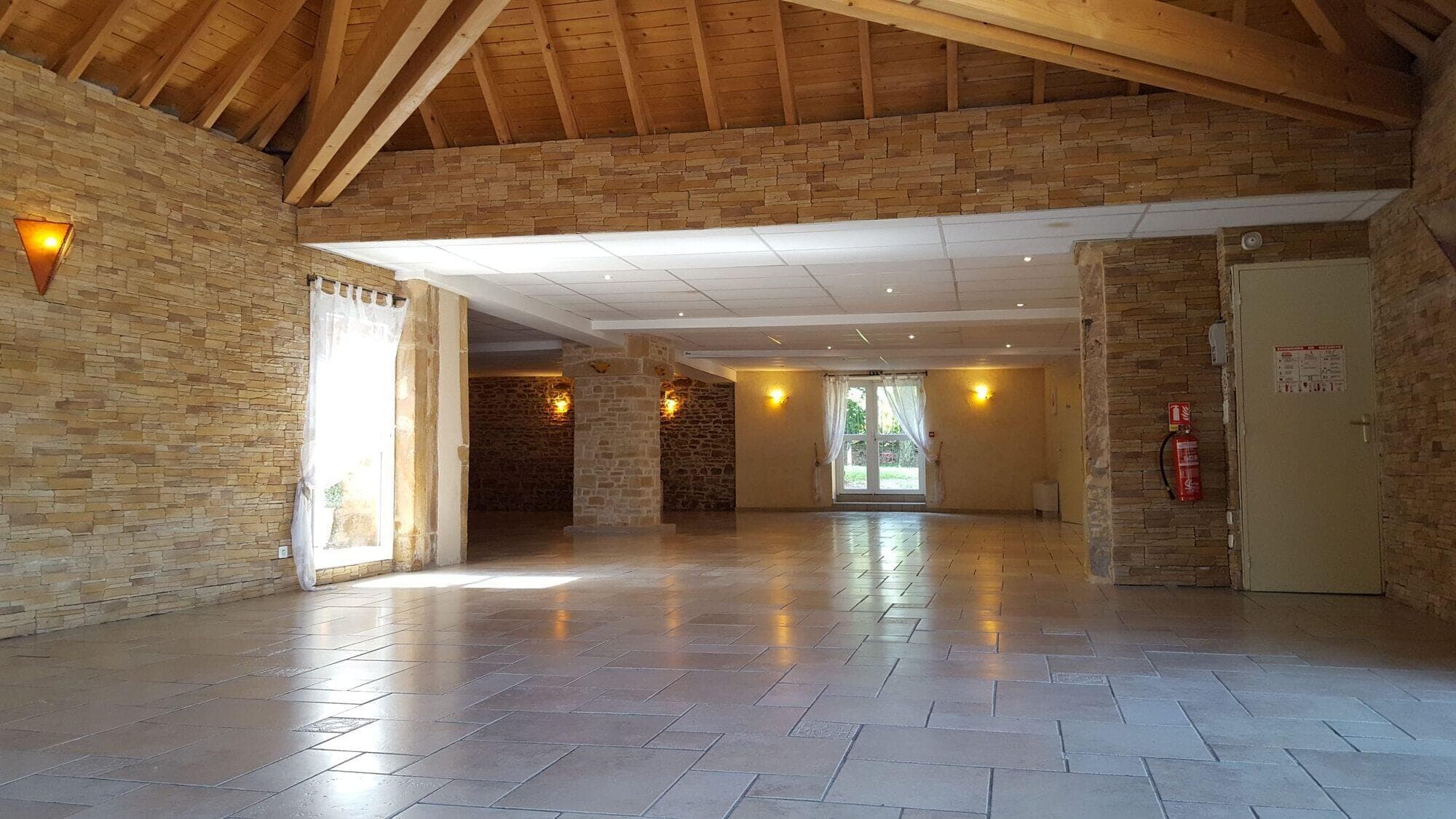 Empty reception hall with stone walls and wooden beams.