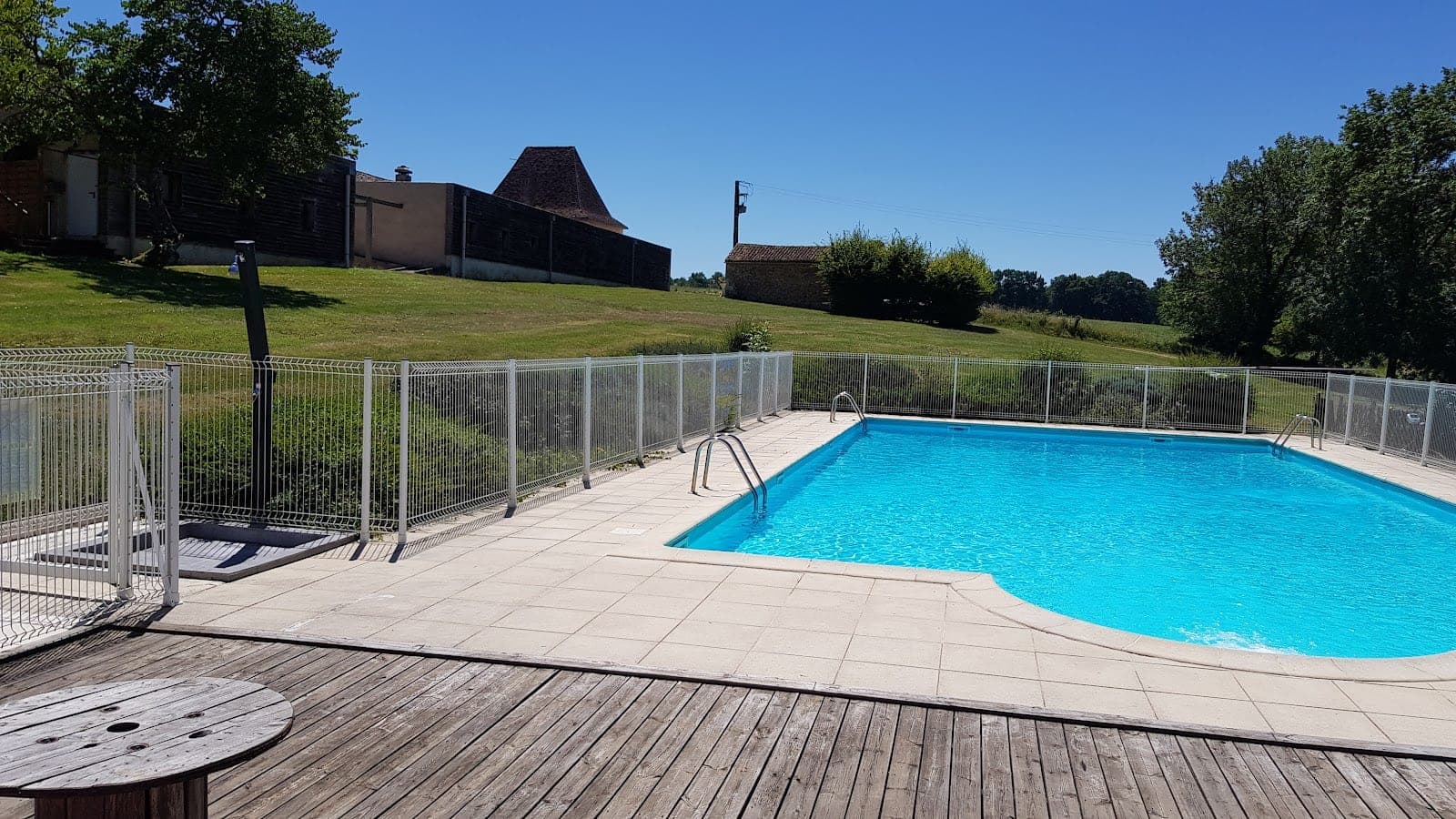 A swimming pool with blue water and a tiled surround, next to a wooden deck.