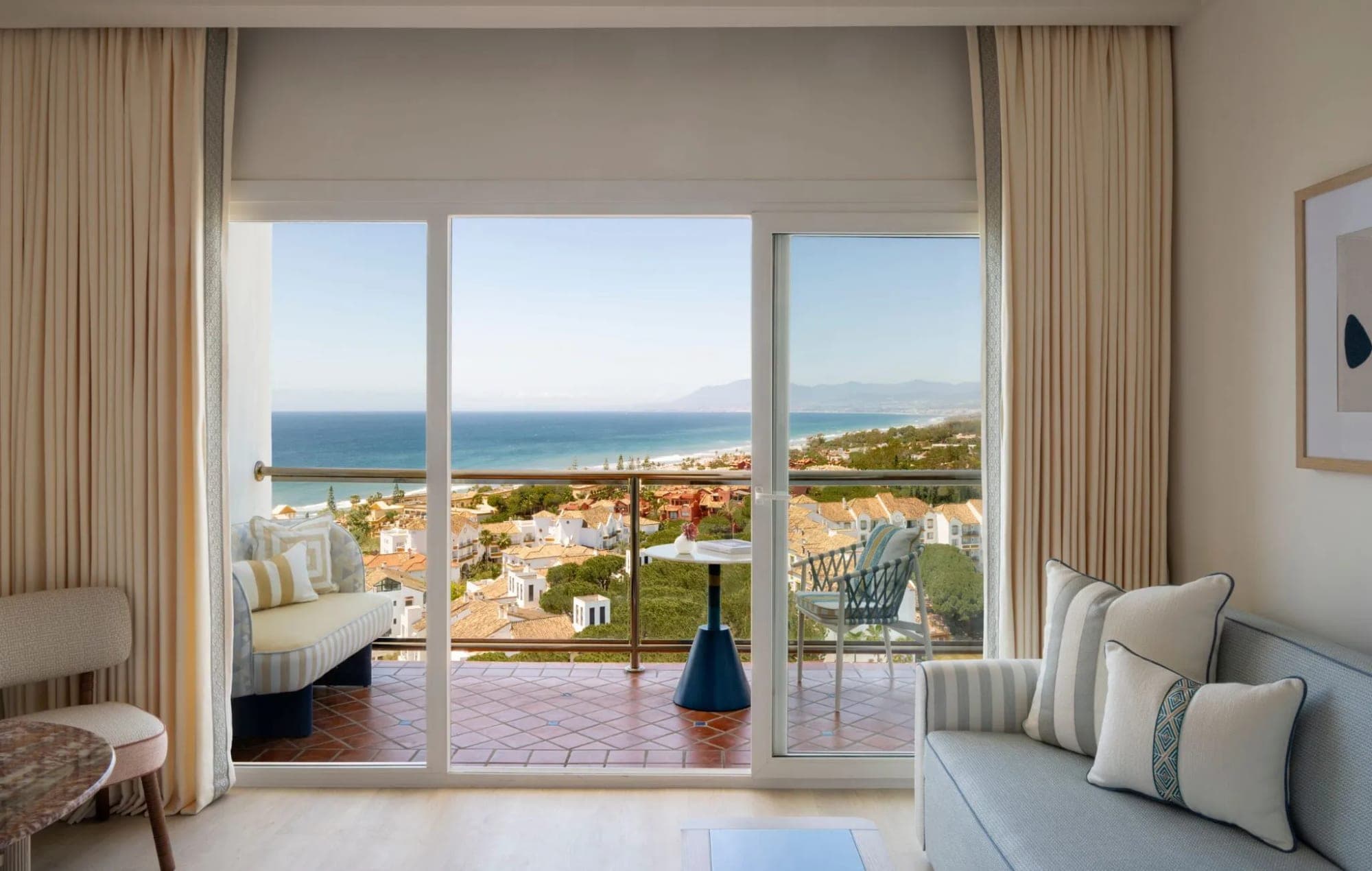 Room interior with a view of the sea and coastal town.
