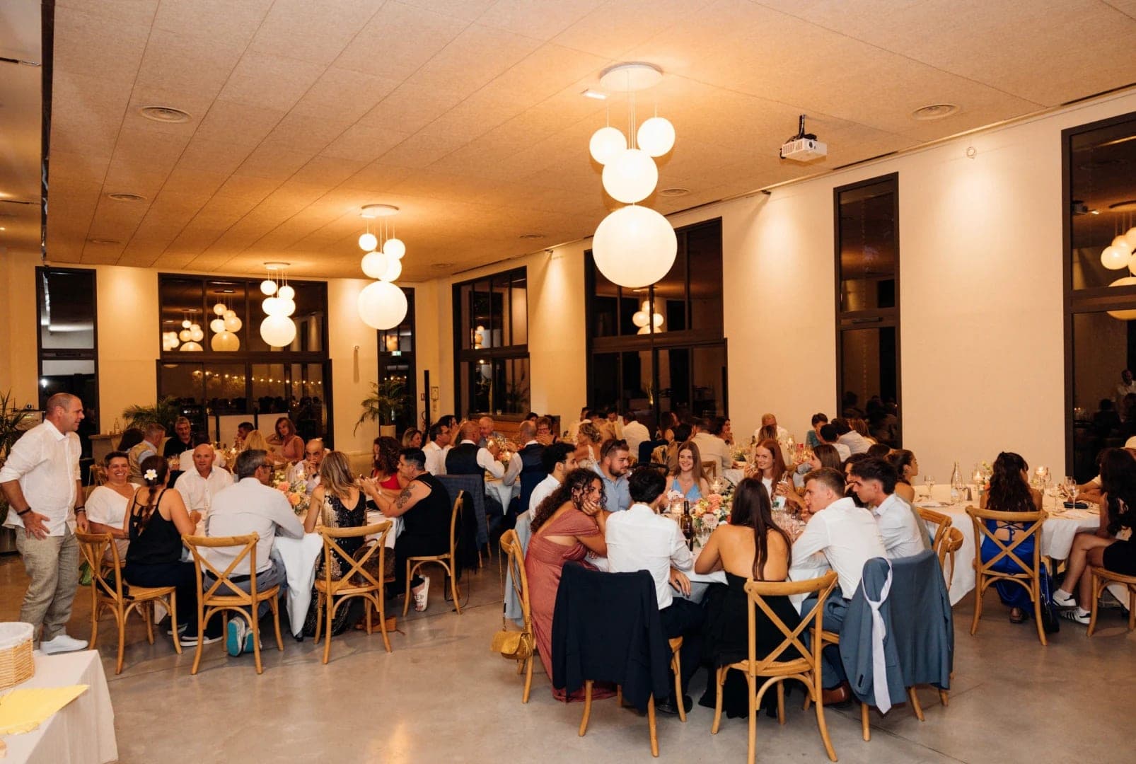 Wedding reception with guests seated at tables in a well-lit room.