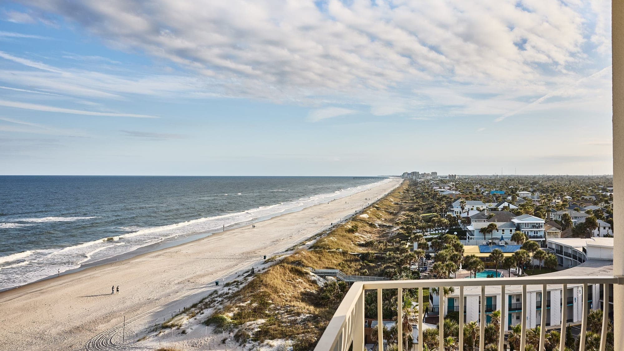 View of a long sandy beach and the ocean from a balcony.