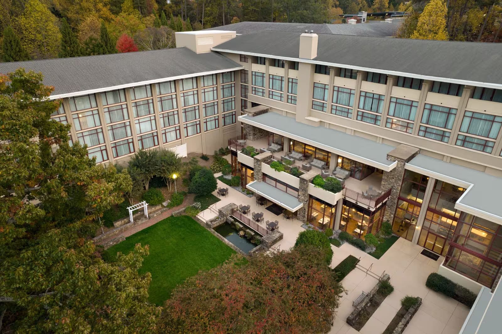 Aerial view of a hotel building with a courtyard and garden.