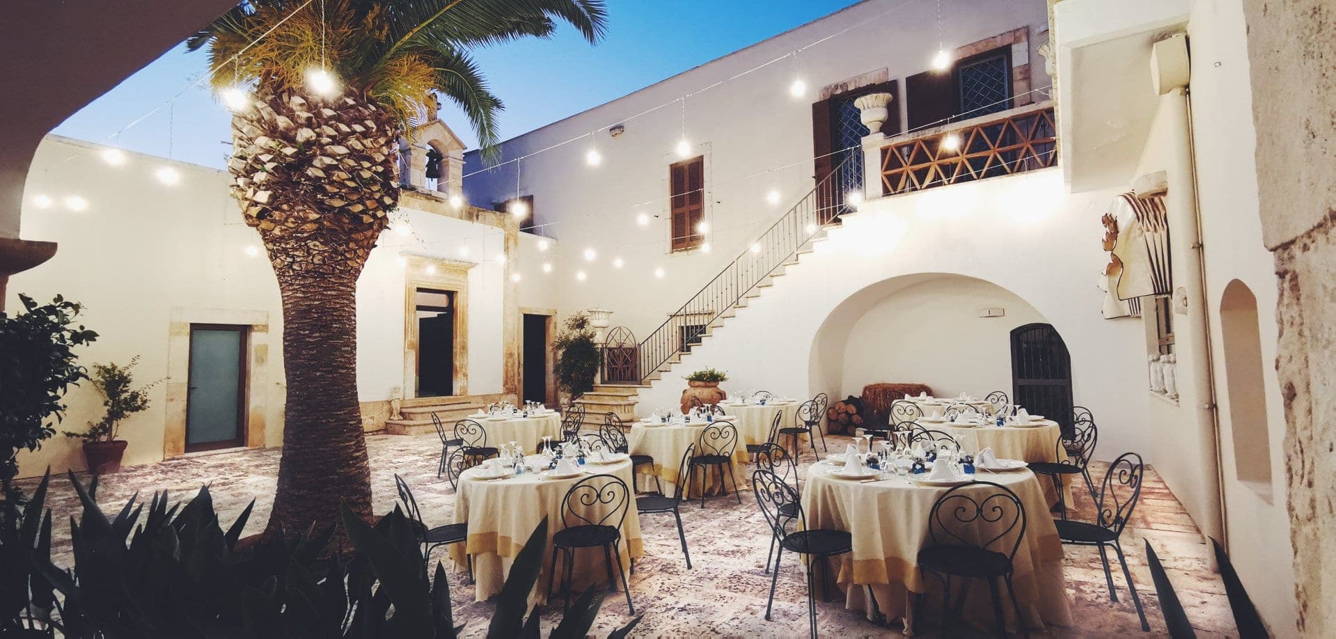 Courtyard with tables set for a reception and string lights overhead.