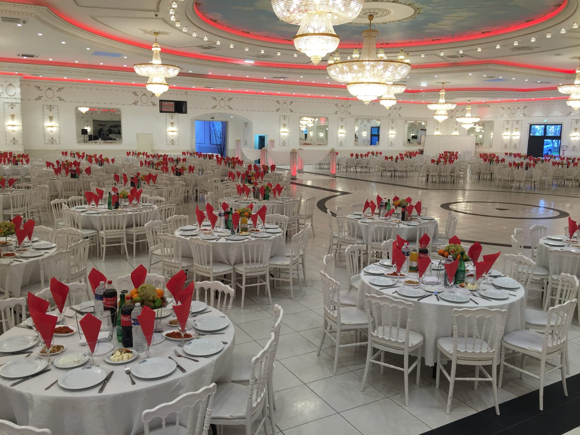 A large reception hall with round tables set for a wedding.