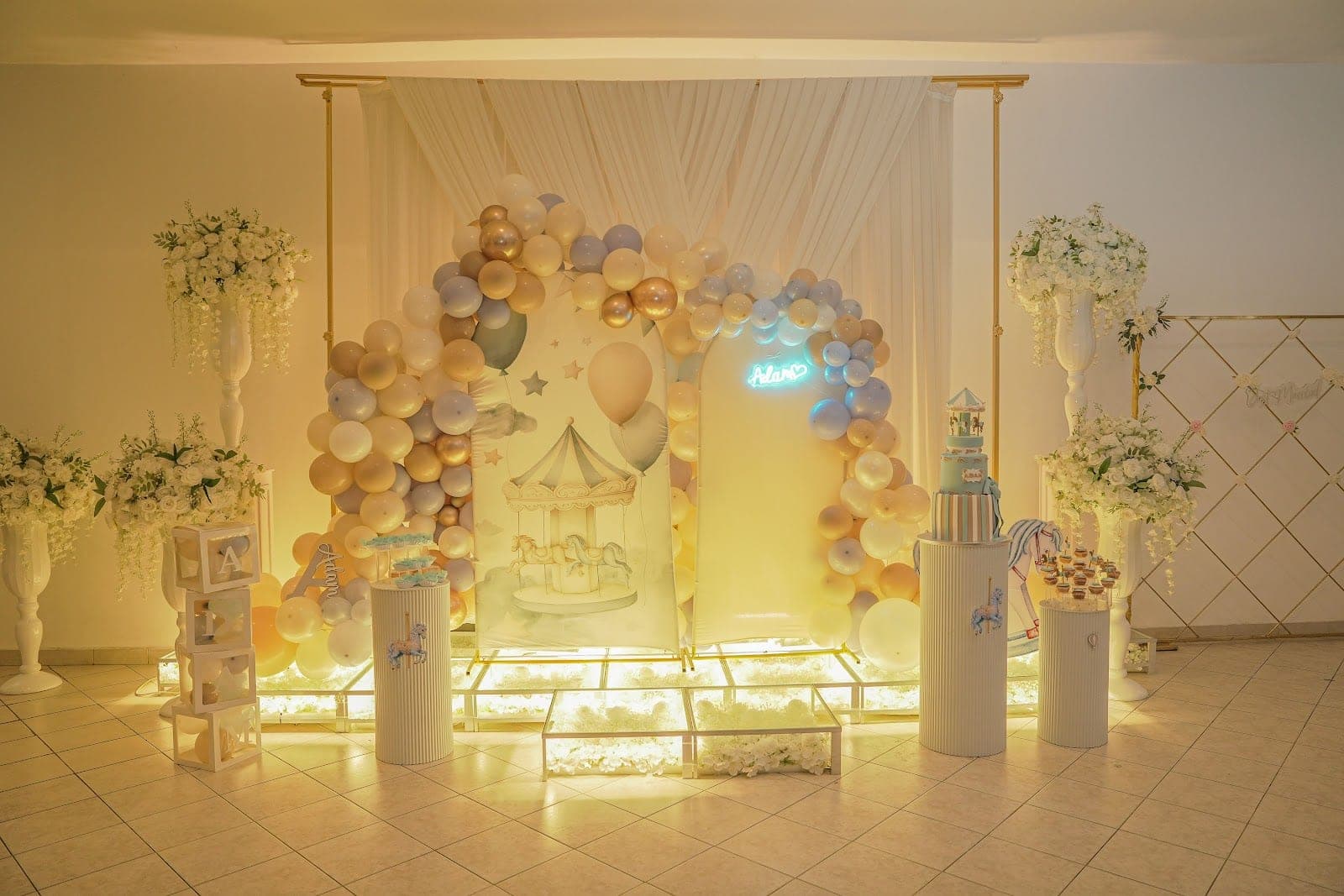 A decorated area with balloons, a cake, and floral arrangements.