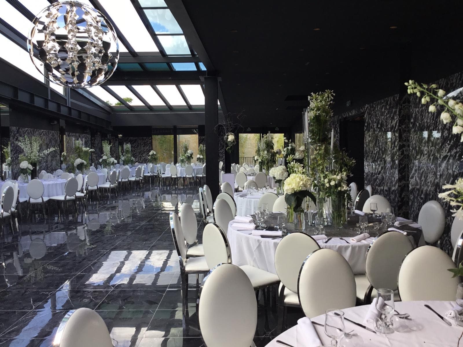 A wedding reception room with tables set for dinner and a large chandelier.