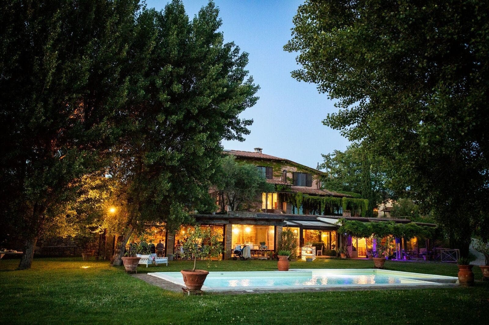 A large building with a swimming pool and garden in front of it.