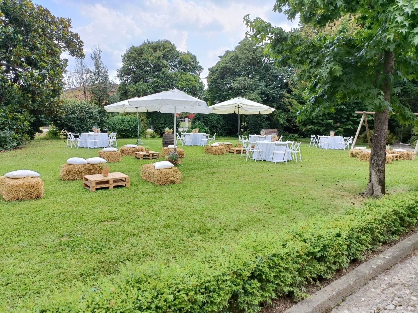 Garden with tables, chairs, umbrellas, and hay bale seating