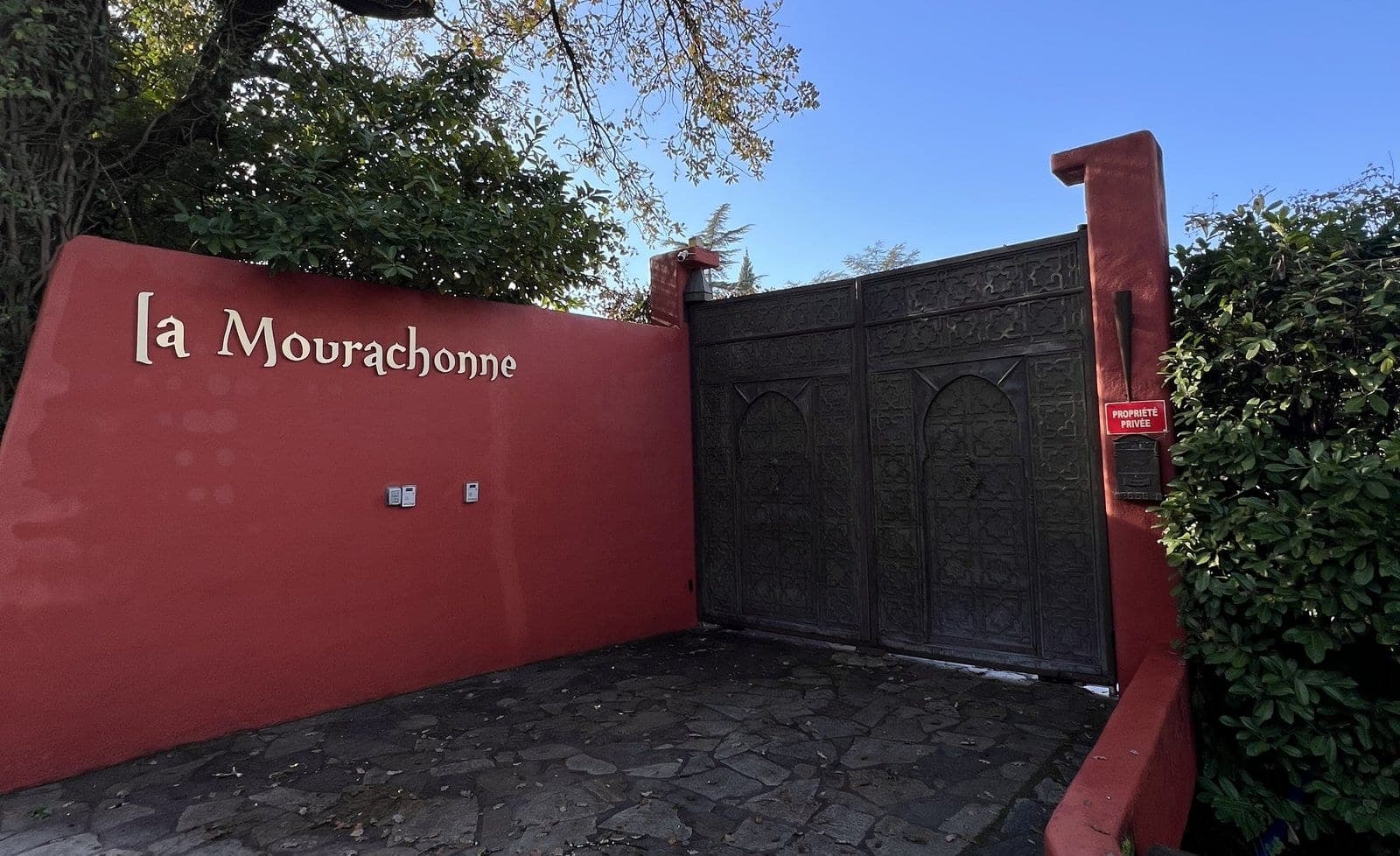 Entrance gate and red wall with venue name 'la Mourachonne'
