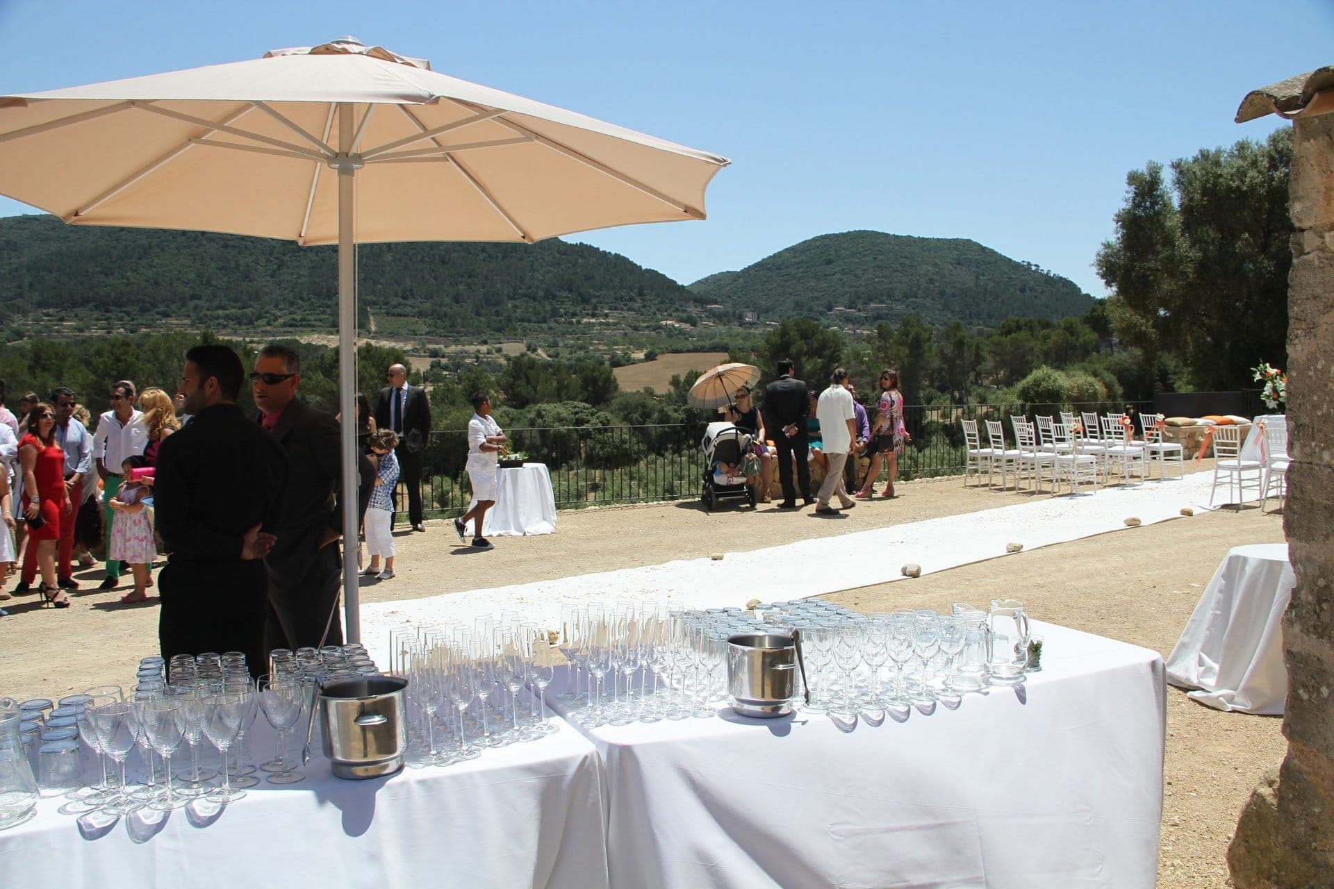 Outdoor wedding ceremony setup with chairs and a white aisle runner, overlooking hills.