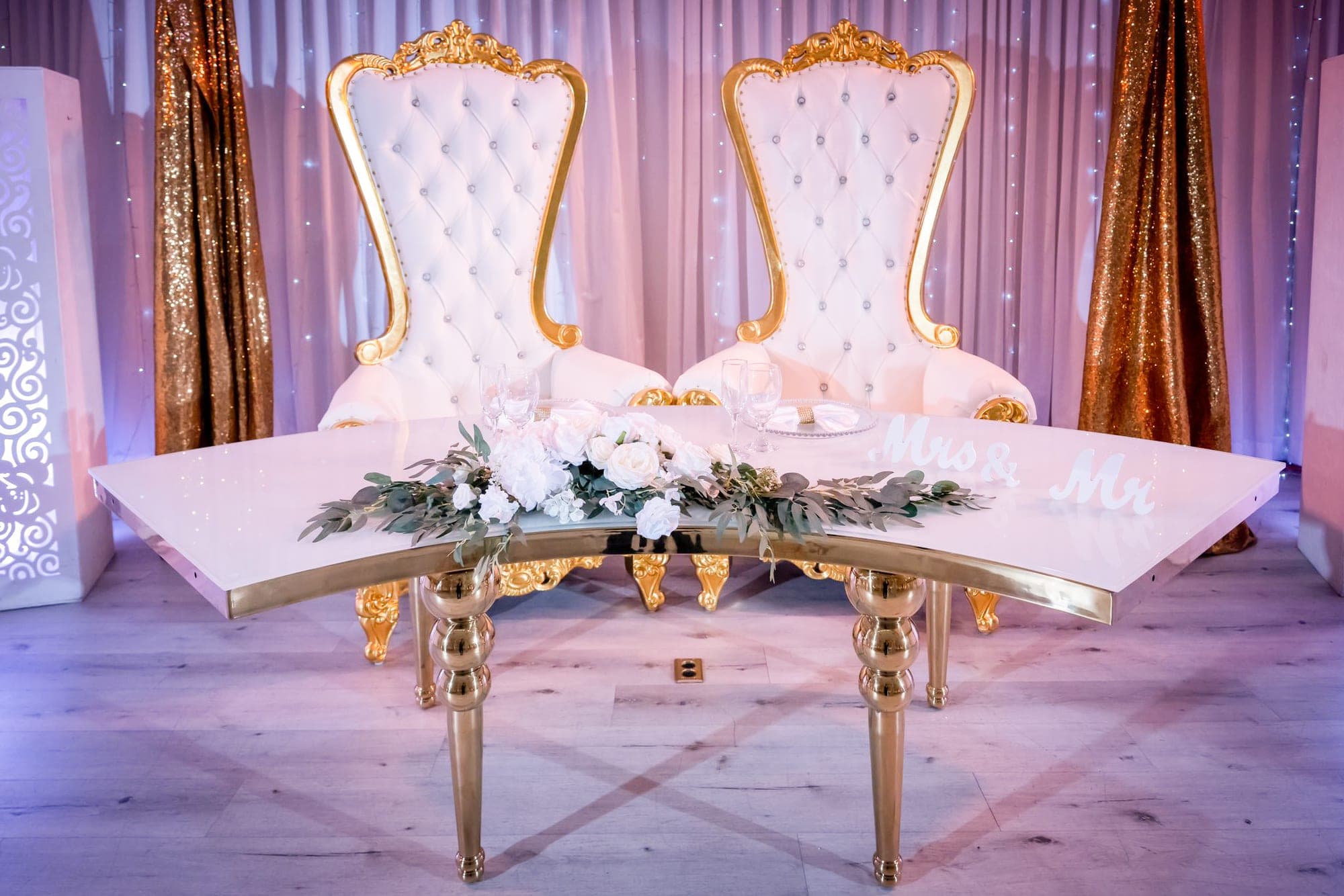 A decorated table with two ornate chairs and floral arrangements.