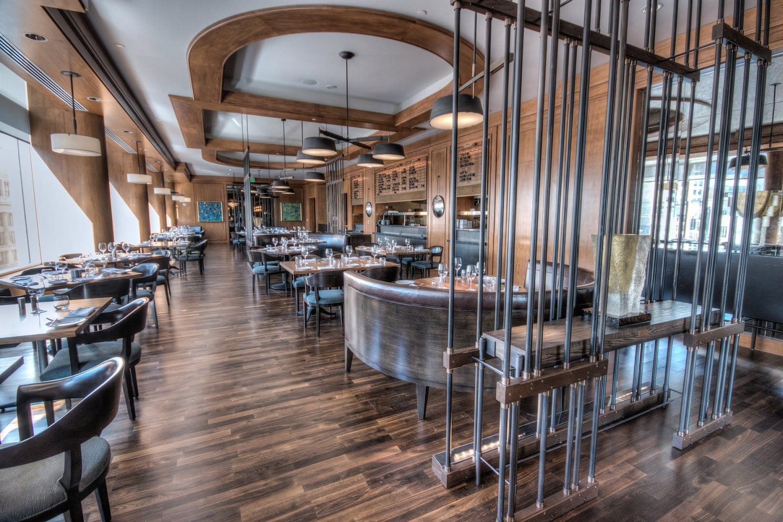 A dining room with tables and chairs, and a bar in the background.
