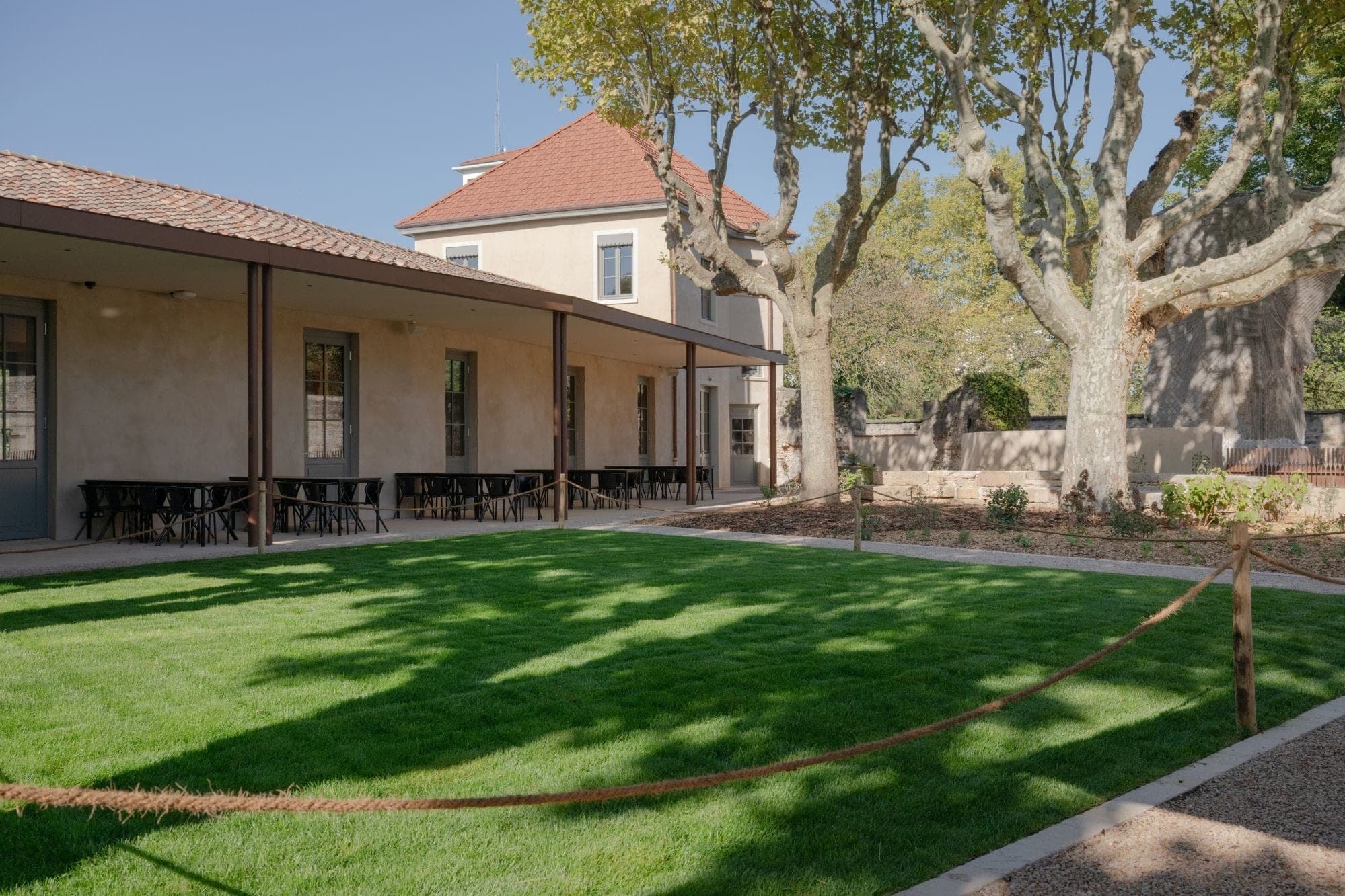 Exterior view of a building with a covered patio and a lawn area.